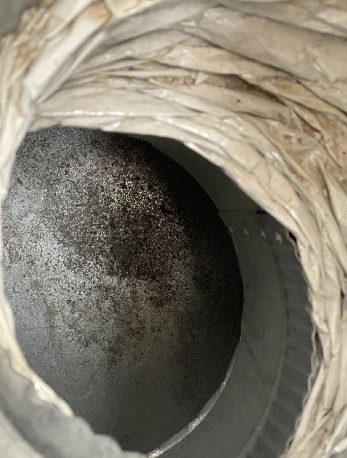 The inside of a cylindrical, metallic object with a dark, oxidized interior surface.