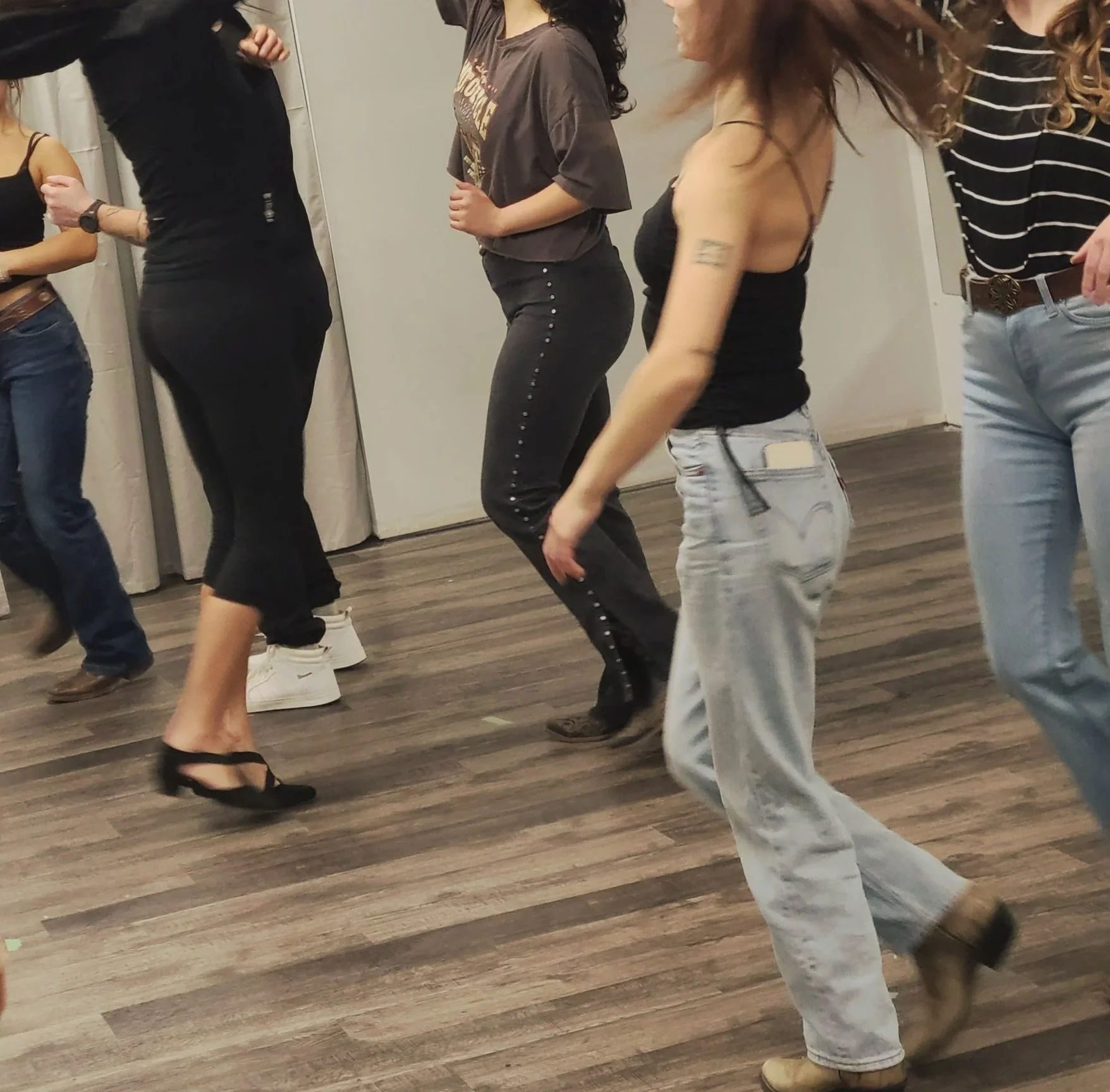 6 dancers dancing in an Okanagan Country Swing class wearing jeans, leggings, loose tee shirts, sleeveless tops, western cowboy boots, sneakers, and dance shoes.