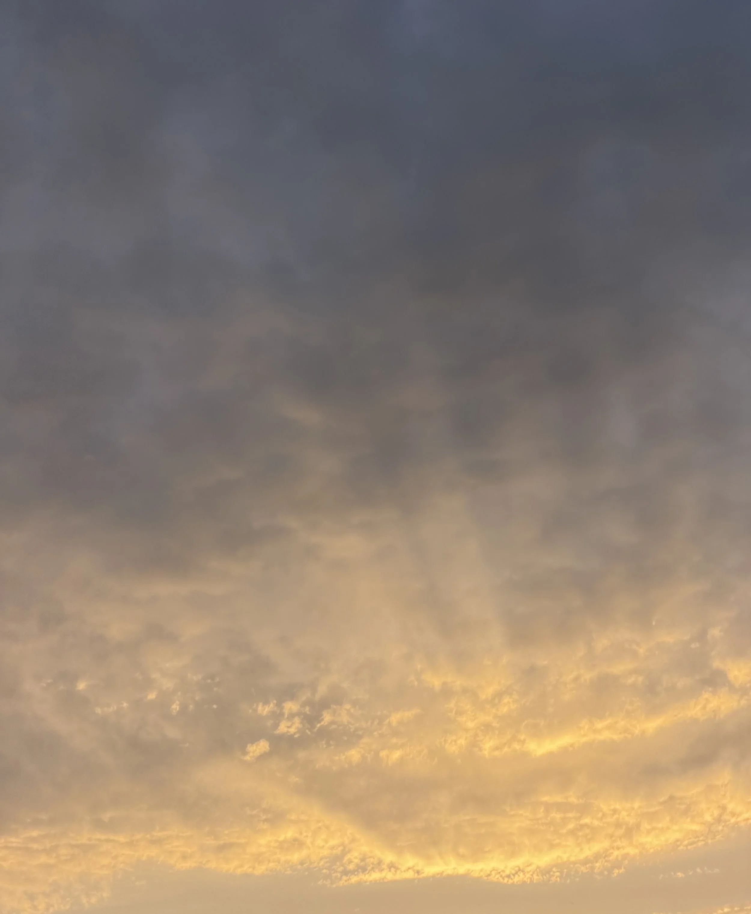 Sky with dark clouds and golden sunlight at sunrise or sunset.