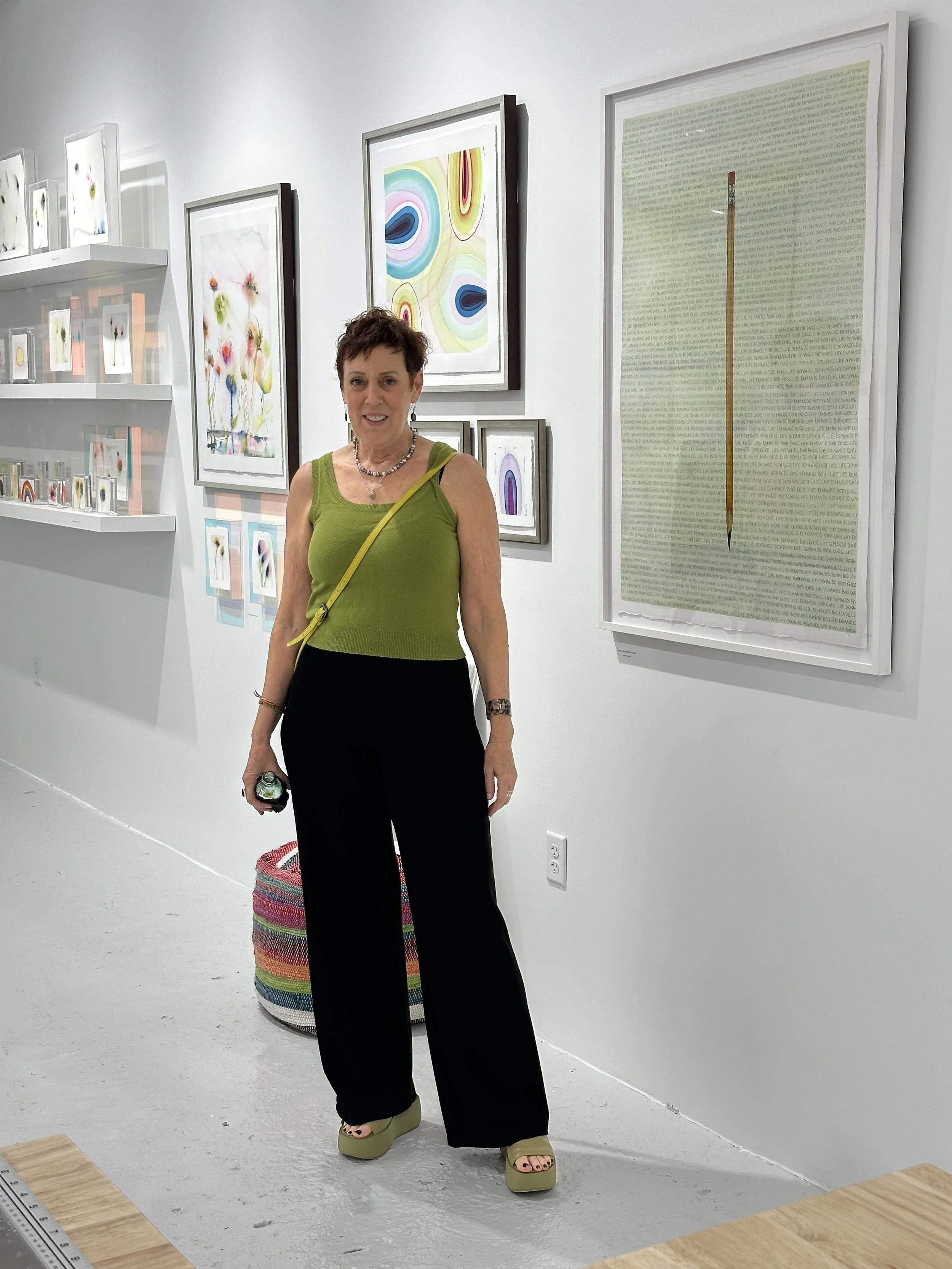 Woman standing in an art gallery with colorful abstract paintings and artwork on the white walls.