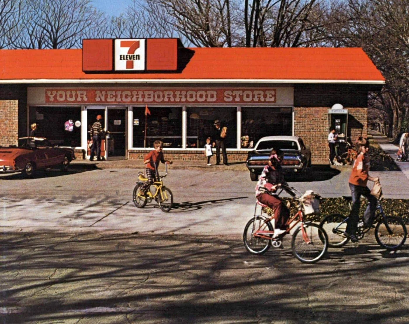 1980s 7-Eleven store with red roof, vintage cars, kids on bikes, and a phone booth — classic suburban scene.