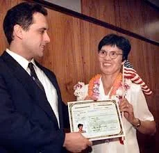 Jie Zhao Li’s mother receiving U.S. citizenship certificate, wearing a floral lei and holding an American flag — emotional milestone in long-term missing child case.