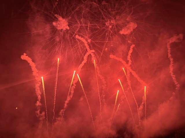 Fireworks exploding in the night sky with trails of red and orange light.