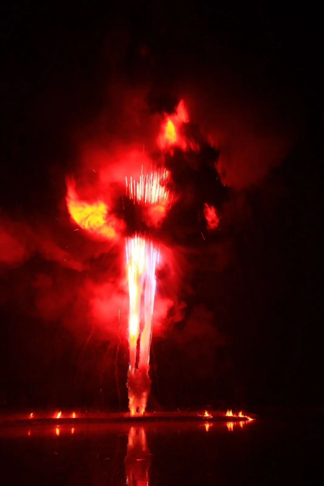 Fireworks exploding in the night sky, illuminating the darkness with red and yellow colors.