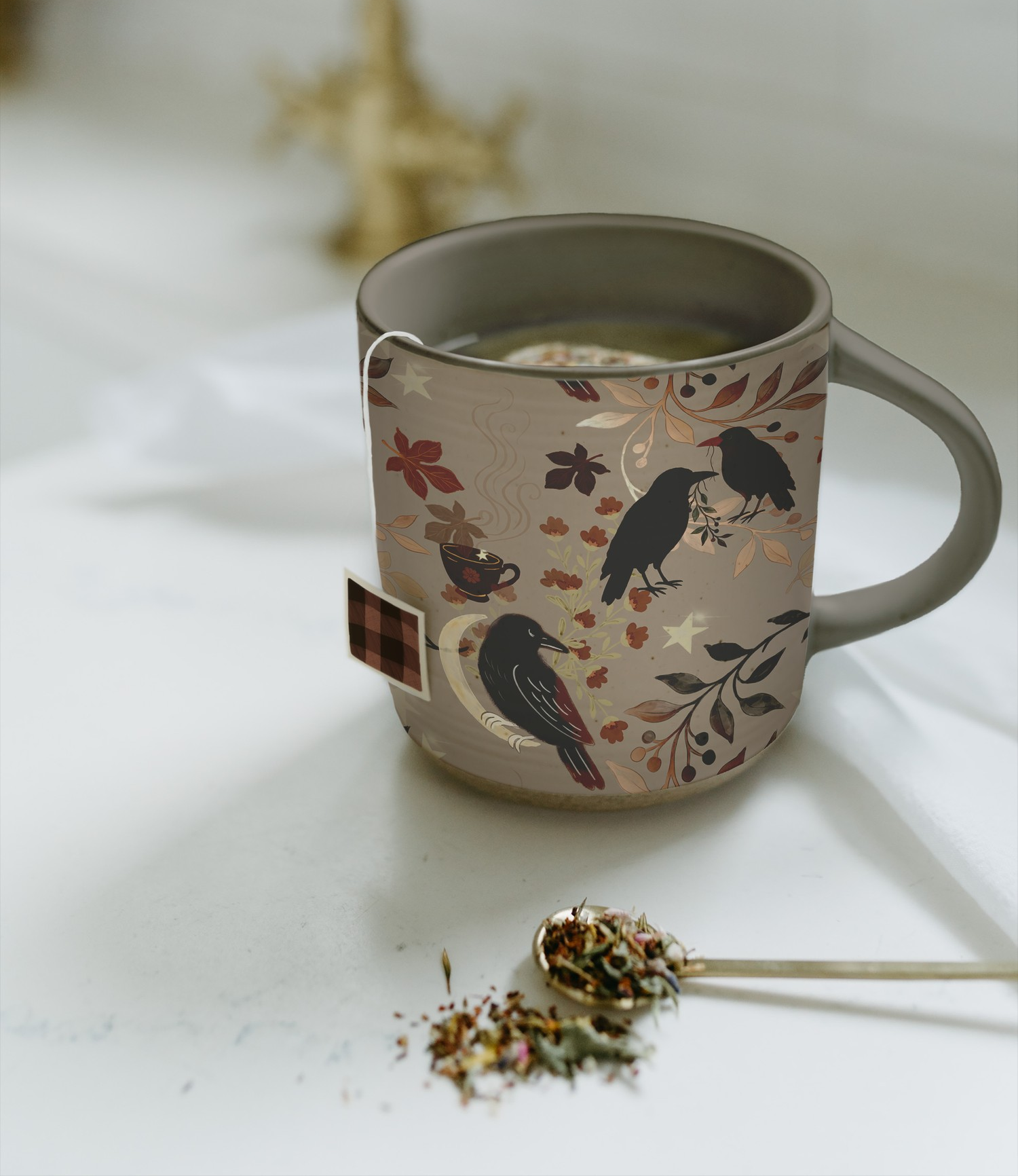 A ceramic mug with bird and botanical surface pattern design, filled with tea and styled with loose leaves—an everyday still life reflecting a cozy handmade lifestyle