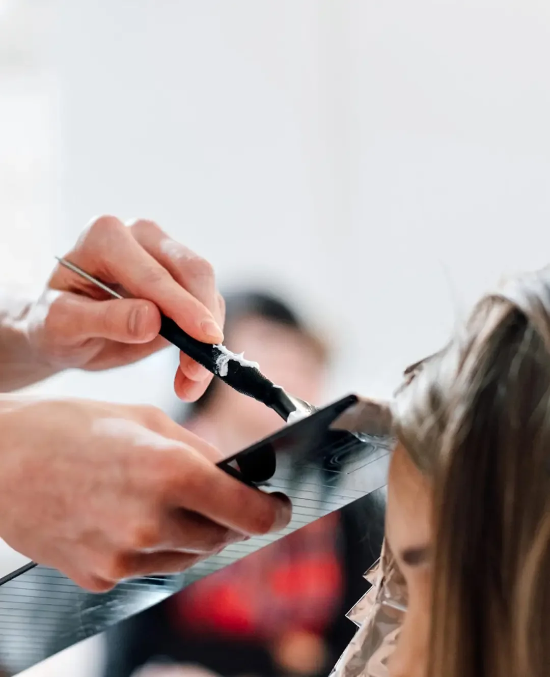 Stylist applying color to retouch roots and cover gray hairs.