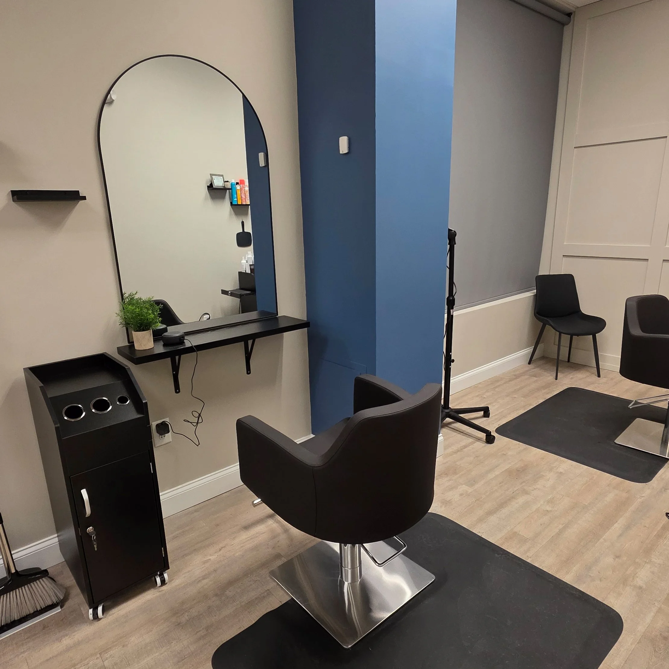 Booth at Signature Strands Hair Studio in Harrisburg, NC with black swivel chair, stylist station, and large arched mirror.