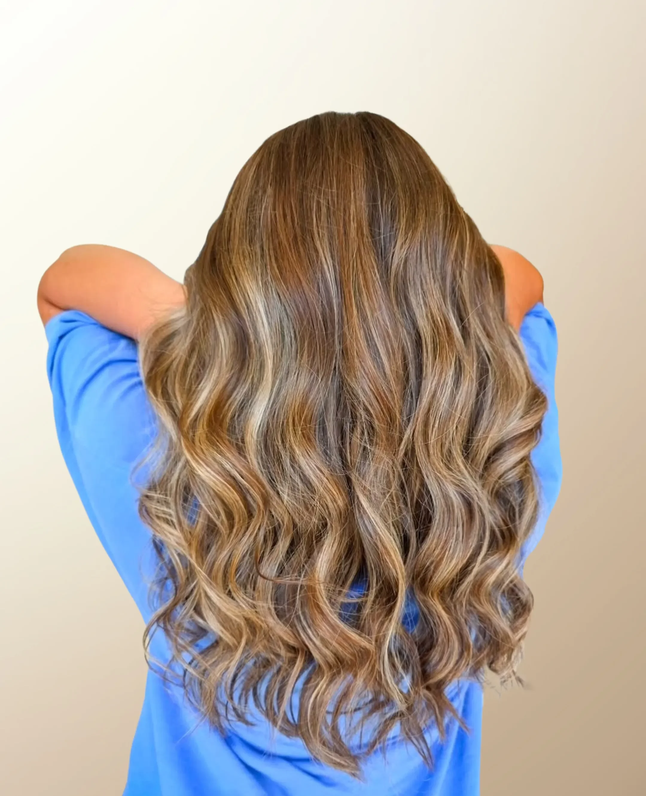 Woman holding soft brown and blonde balayage highlights at Signature Strands Hair Studio, Harrisburg, NC.