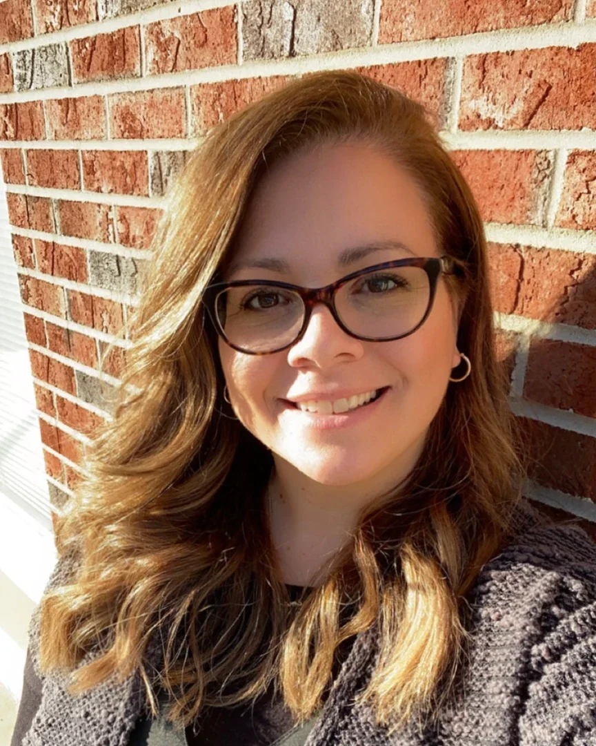 Melissa standing in front of a brick wall.