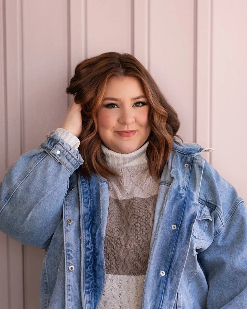 Hannah posing in front of a pink wall.