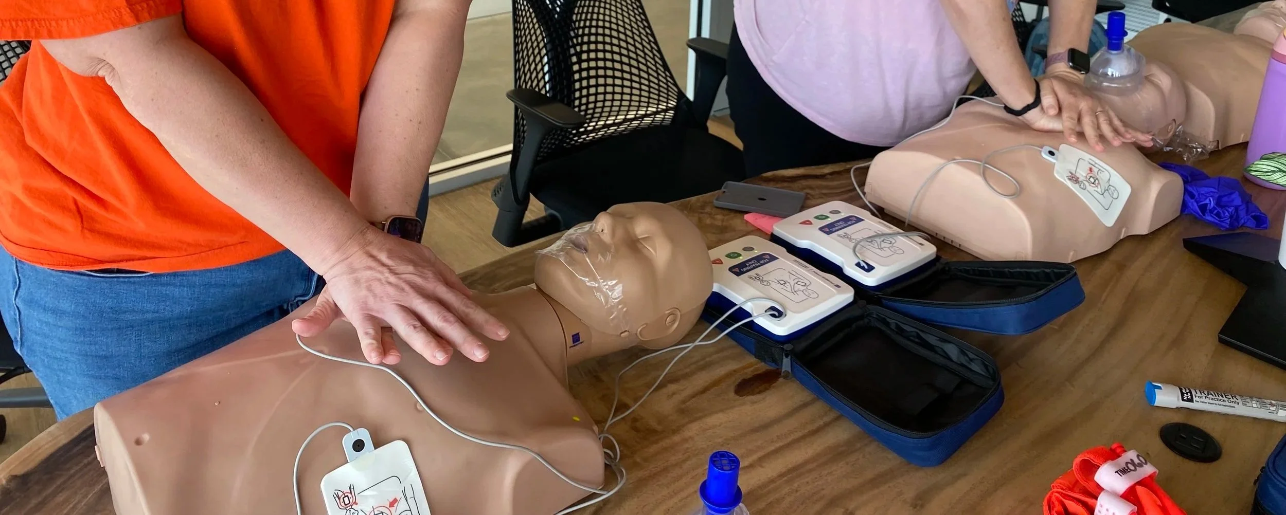 A close-up view of hands performing chest compressions on a CPR training manikin during a hands-on certification class with FACTS in Lakeland, Florida.