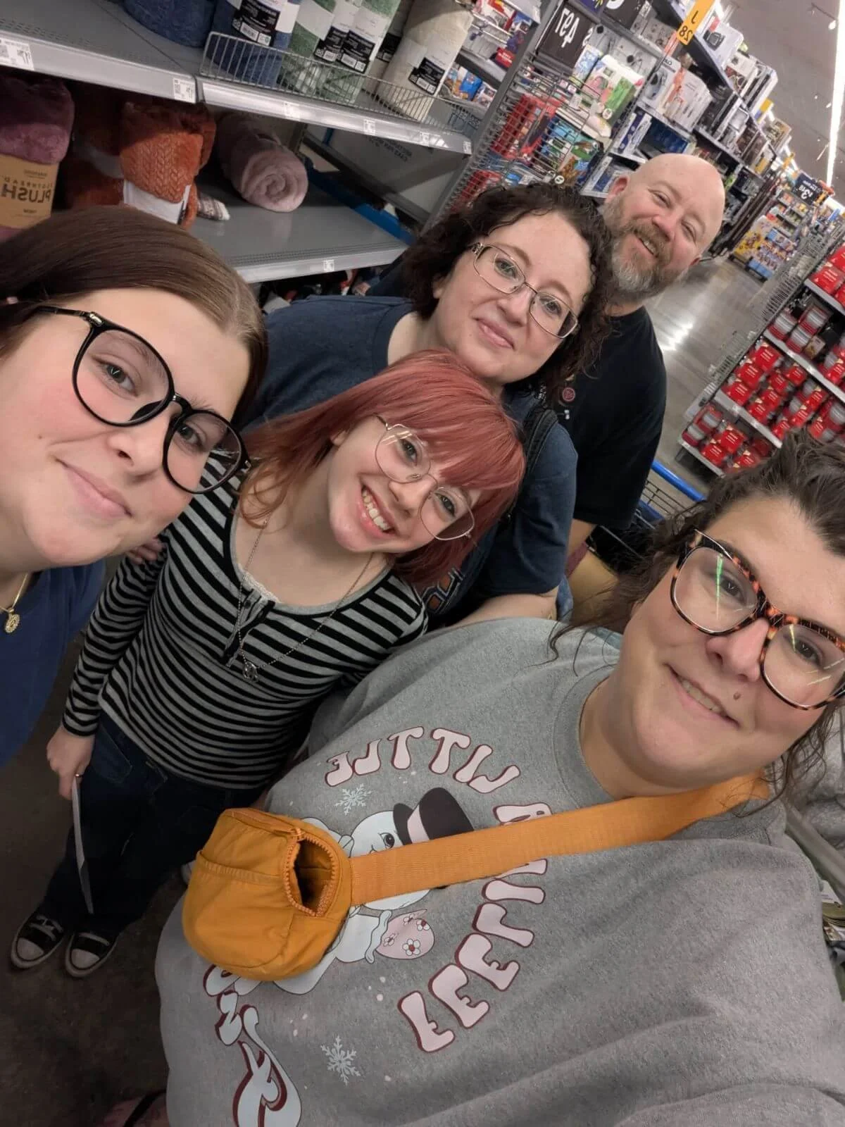 Group of five people taking a selfie in a store aisle with shelves of products in the background.