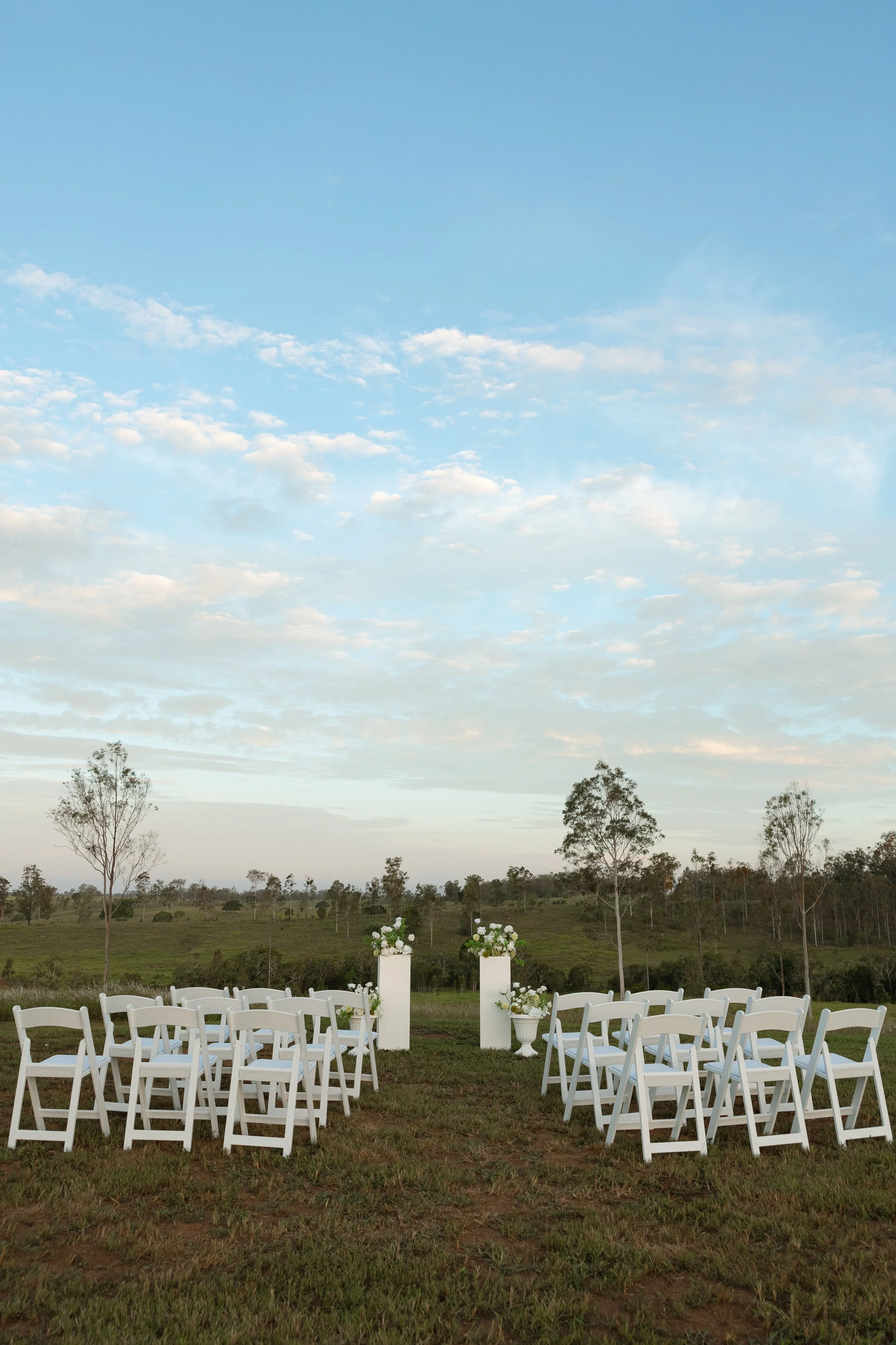 Elopement ceremony setup in Hervey Bay with 20+ chairs and floral styling on plinths for luxury intimate weddings.