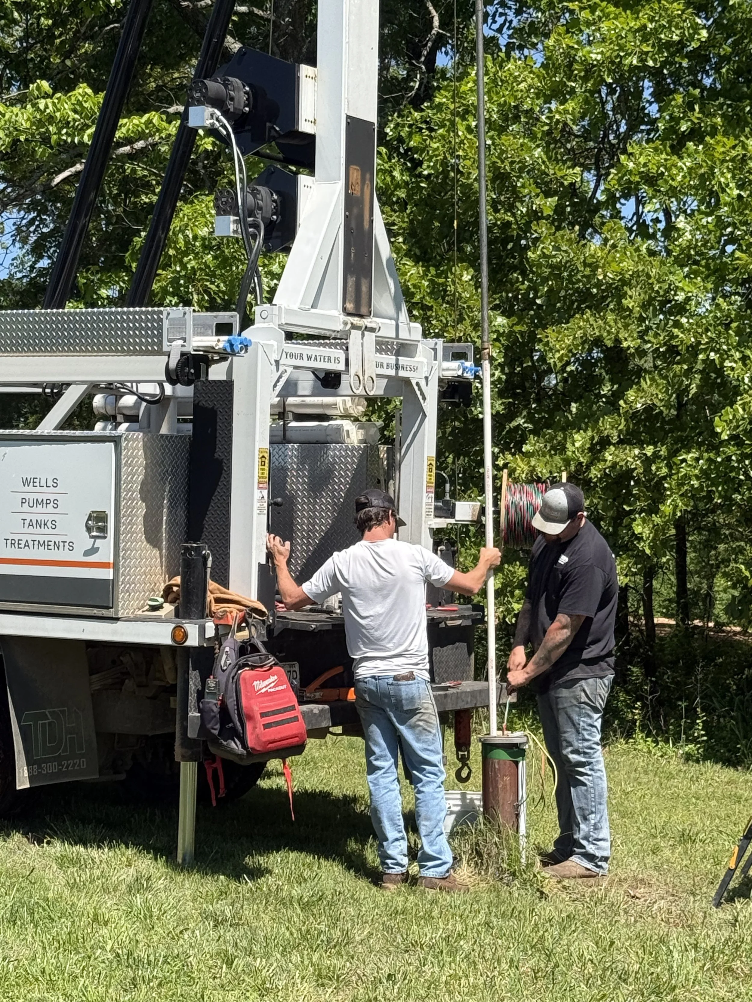 Crew pulling a water well pump.