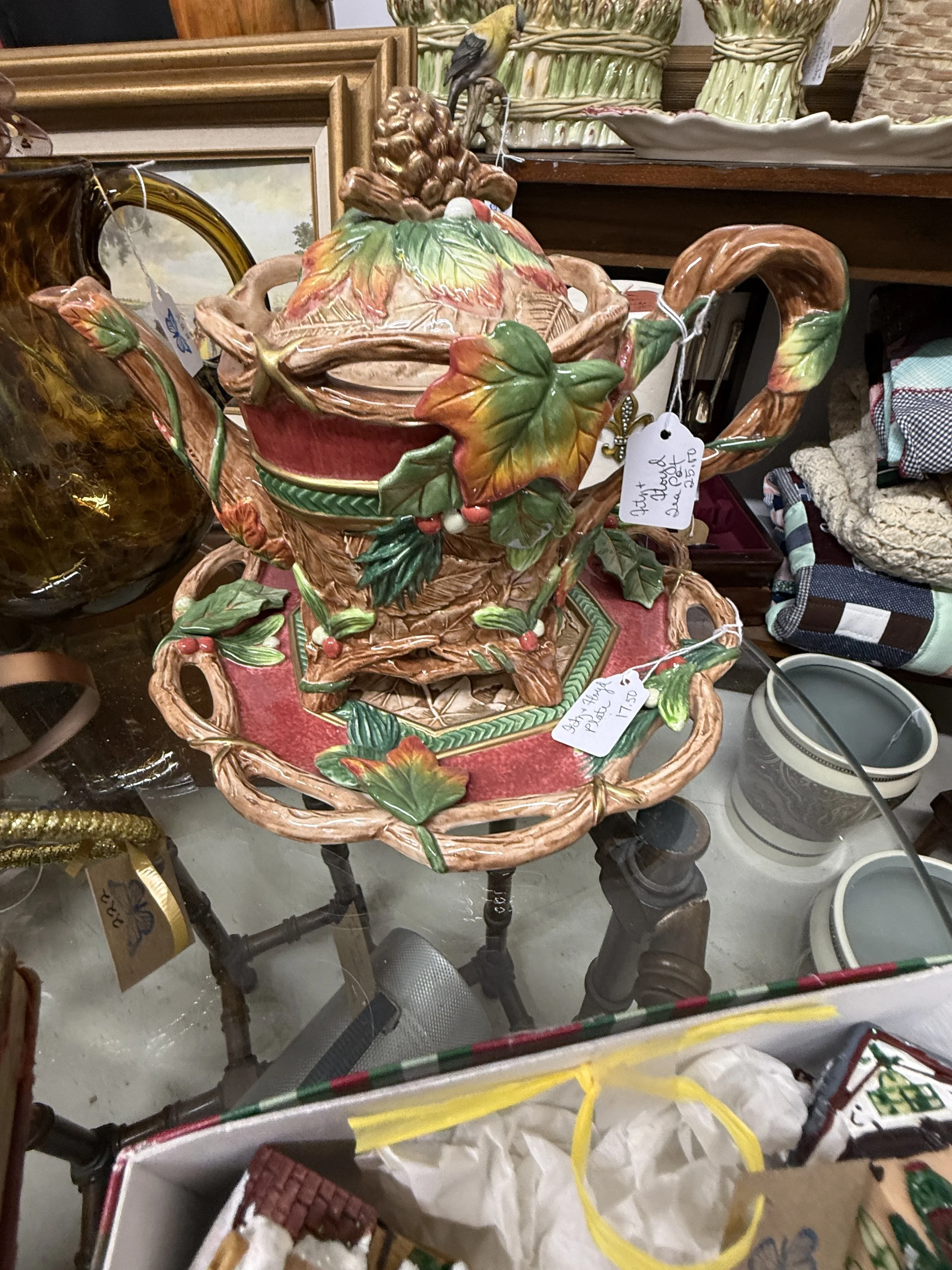 Ornate ceramic fruit basket centerpiece with colorful leaves and flowers, displayed among antiques in a thrift store