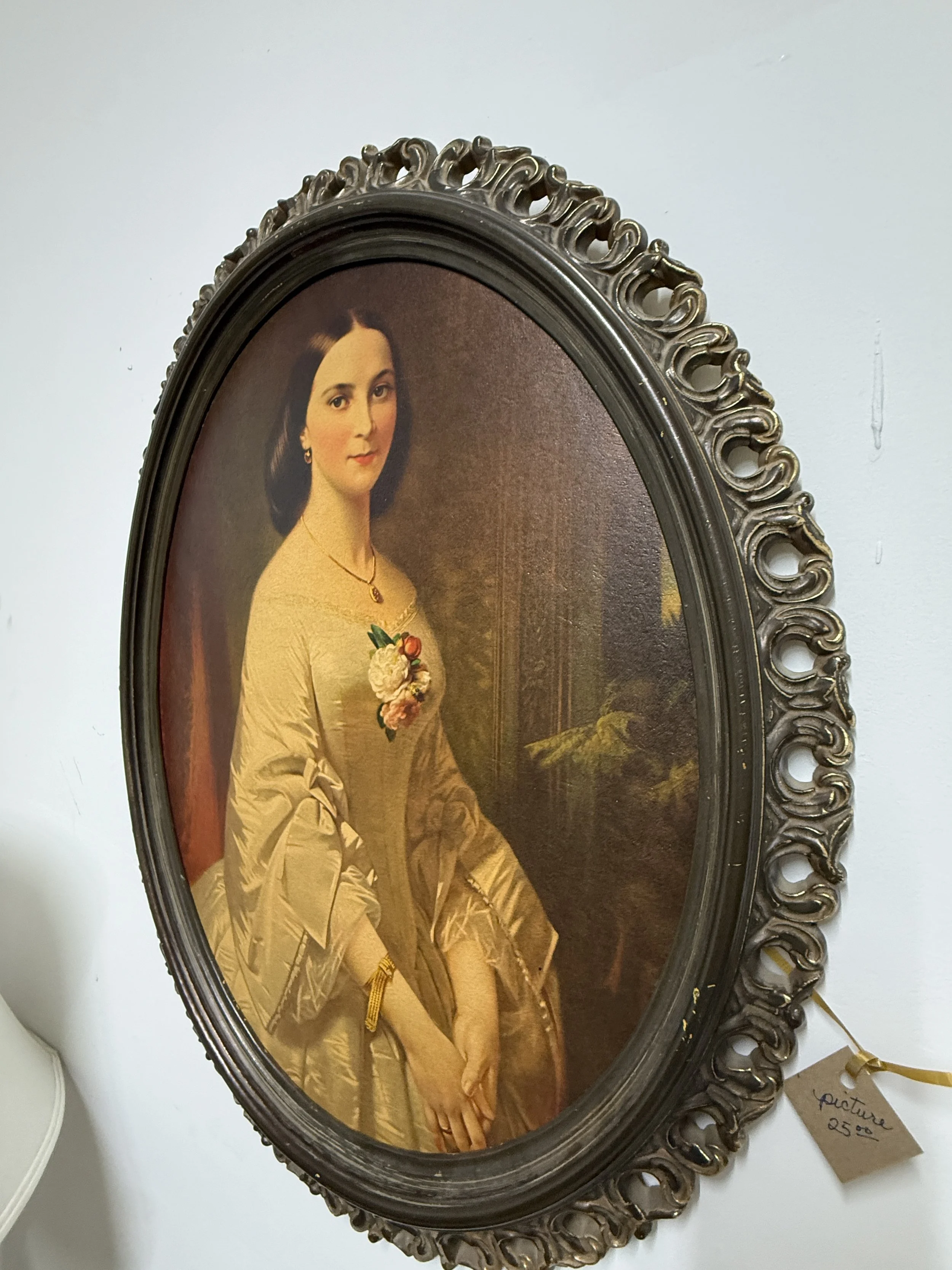 Antique oval portrait of a woman in a yellow dress with flowers, set in an ornate dark carved frame