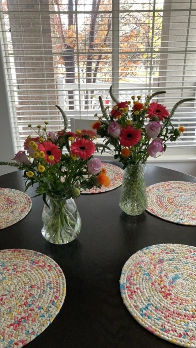 Table with two flower arrangements with various flowers of different colors