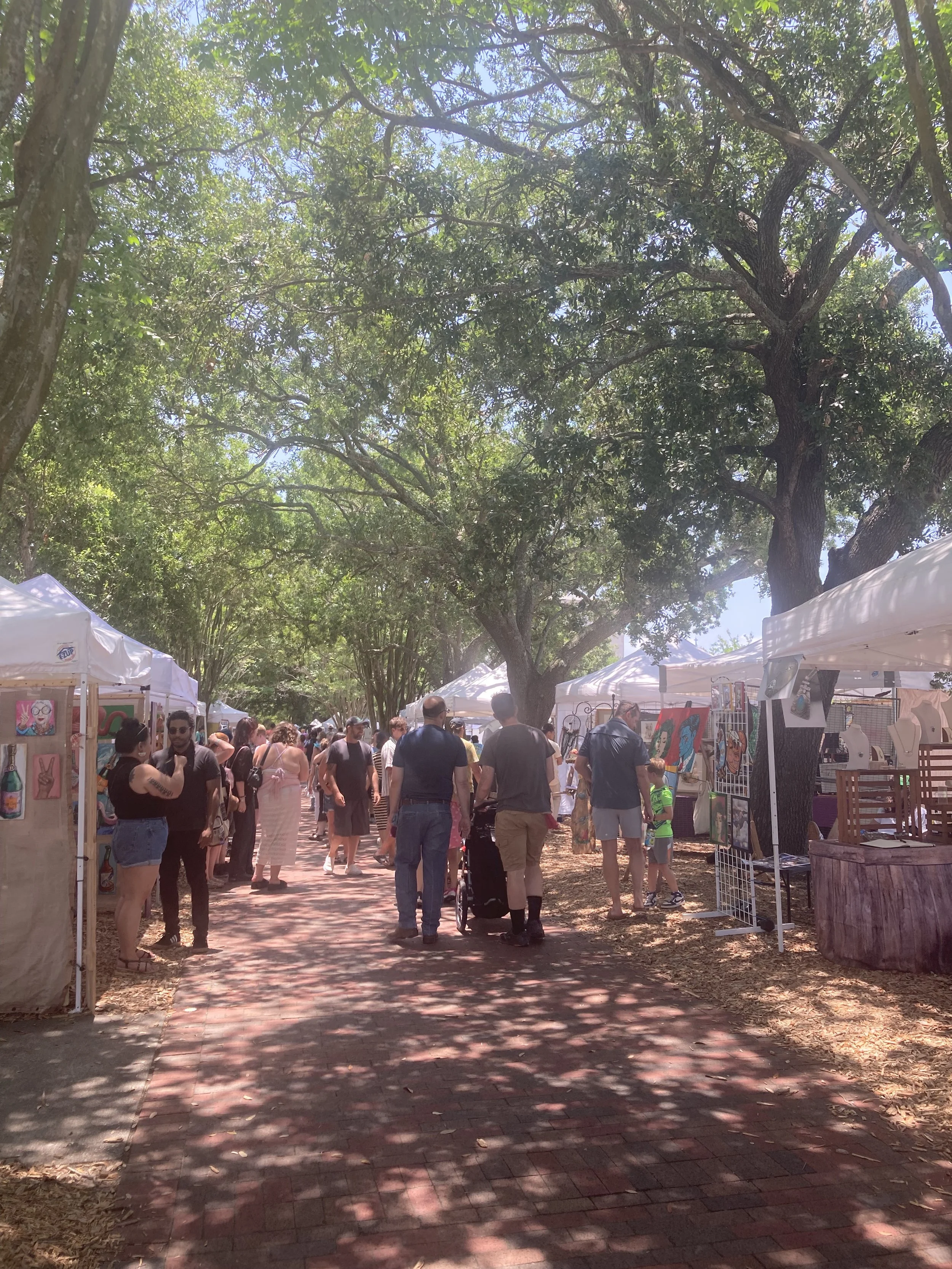 Farmers market in the park with white tents and lots of people