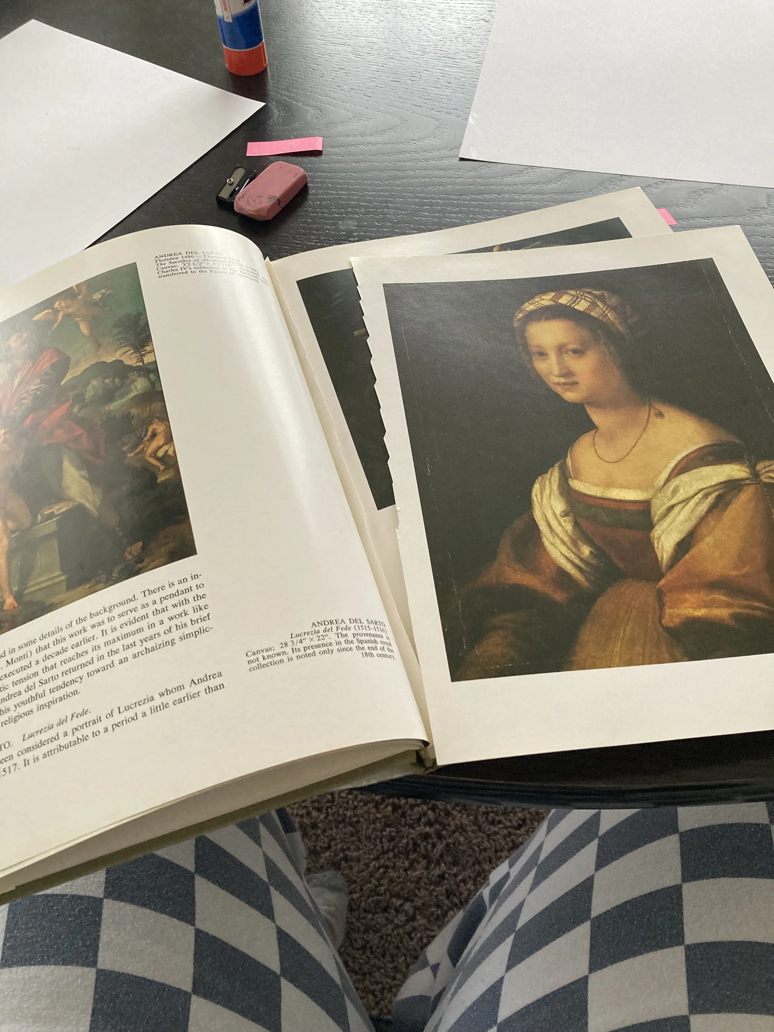 Book laid open on a table with a page ripped out that has a painting of a woman printed on the page