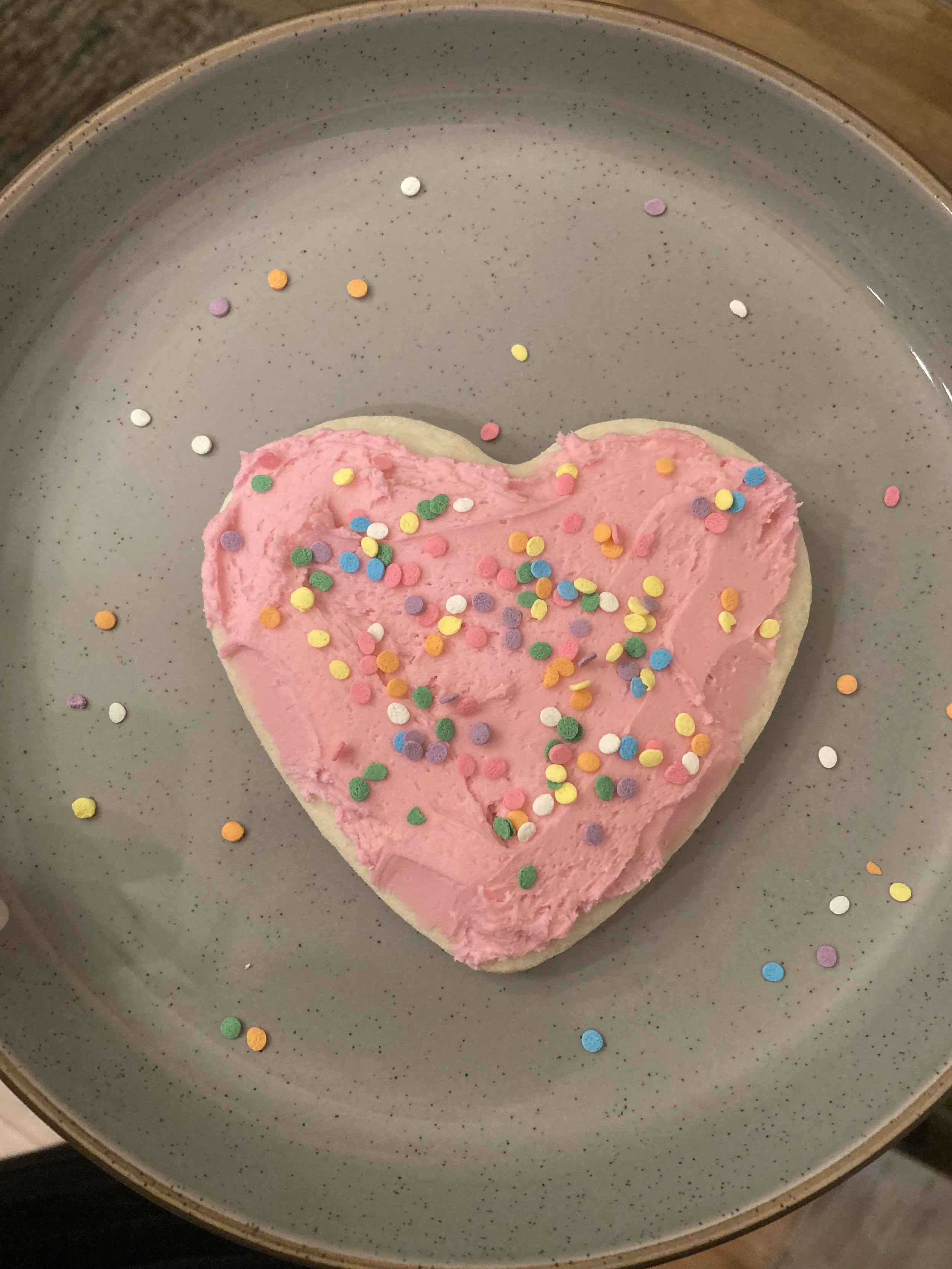 Heart shaped sugar cookie with pink frosting and confetti sprinkles