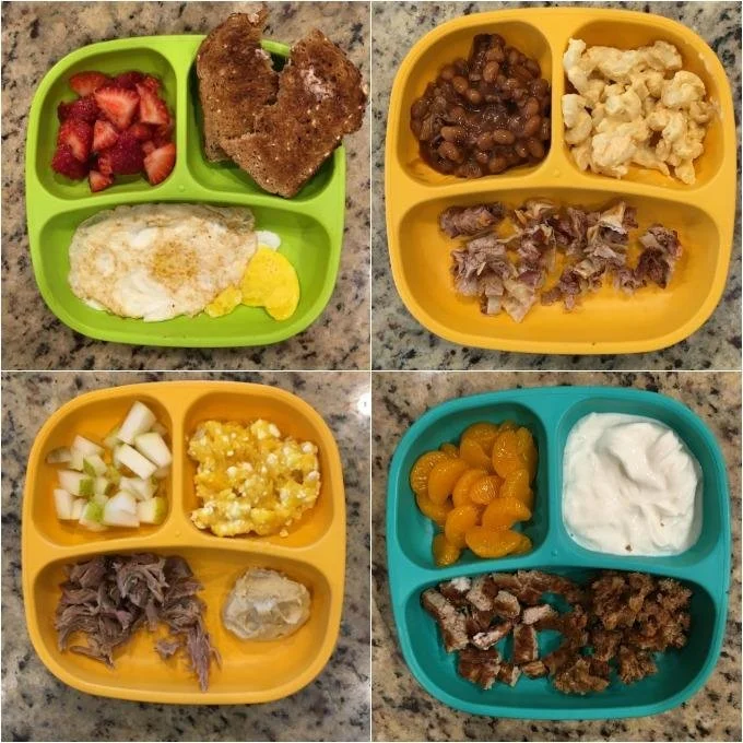 Four colorful divided meal plates each with different food items. The green plate has strawberries, breaded pork chops, scrambled eggs, and a lemon wedge. The yellow plate contains baked beans, macaroni and cheese, shredded beef, and a meatloaf slice
