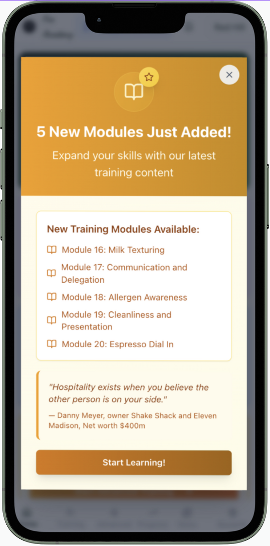 Mobile screen displaying a notification about five new training modules in a learning app, including topics like Milk Texturing, Communication and Delegation, Allergen Awareness, Cleanliness and Presentation, and Espresso Dial In, with a quote from D