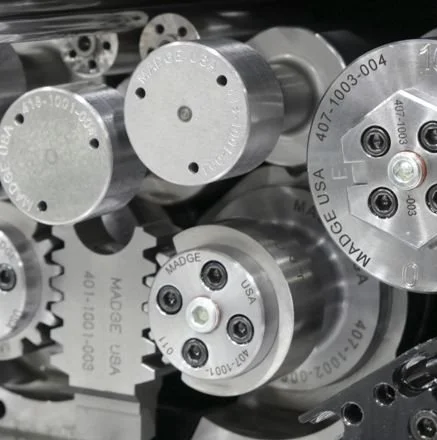 Close-up of multiple metal industrial couplings with engraved text, some featuring bolt patterns and circular holes, arranged on a metallic surface.