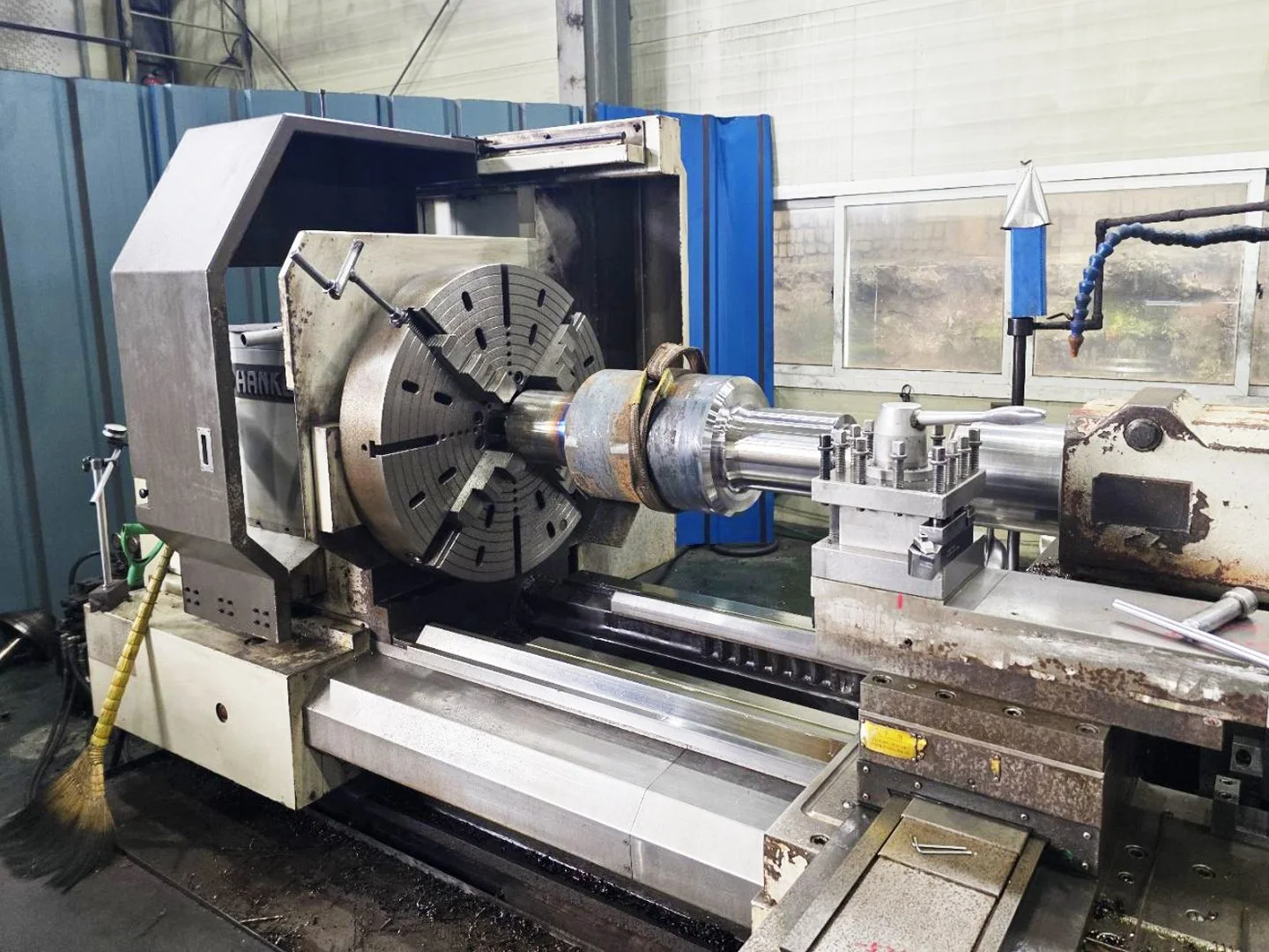 Industrial CNC lathe machine machining a metal workpiece in a workshop.