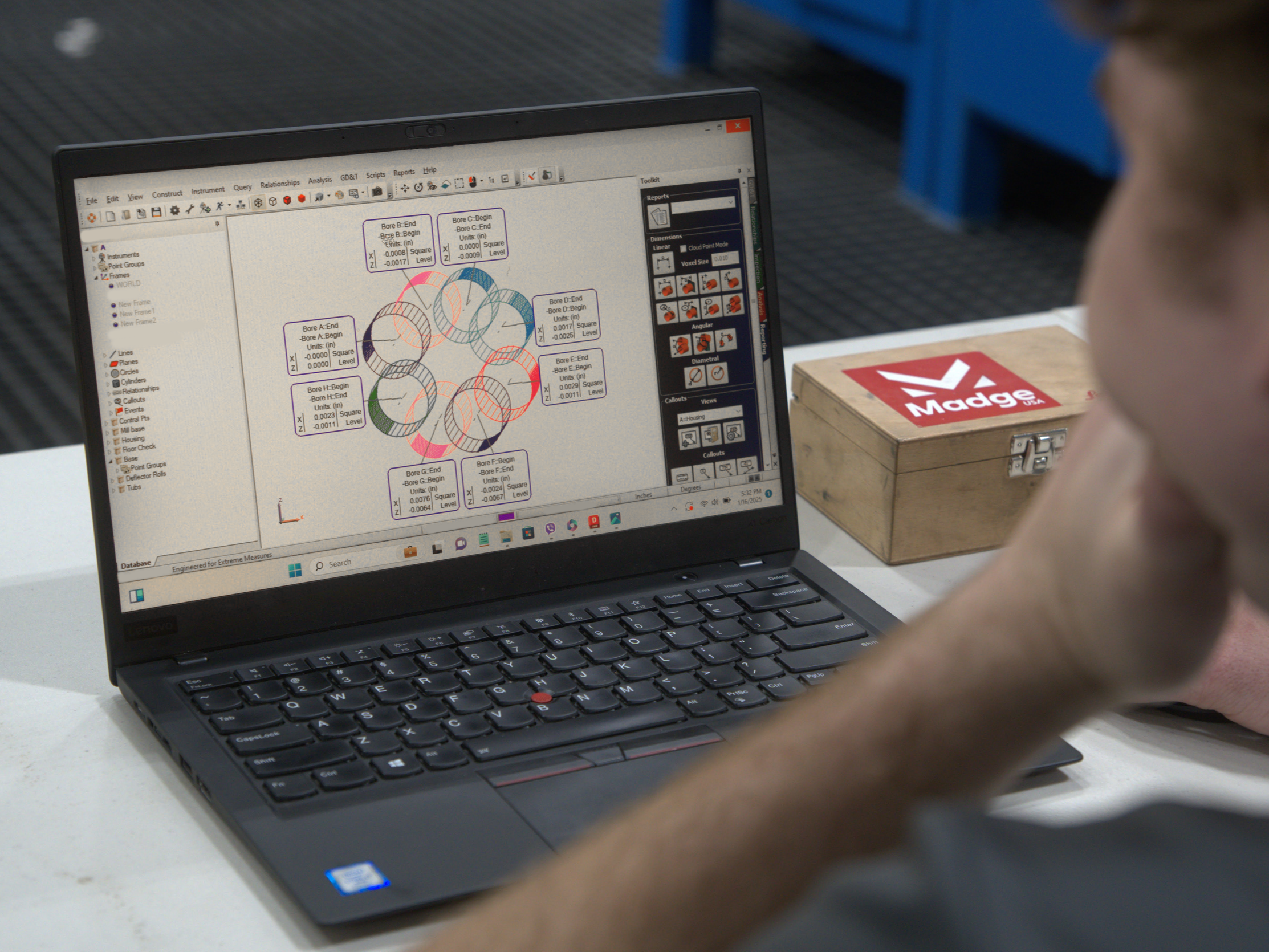 Person working on a laptop displaying a CAD design with circles and measurements, Australian flag sticker on the wooden box beside.