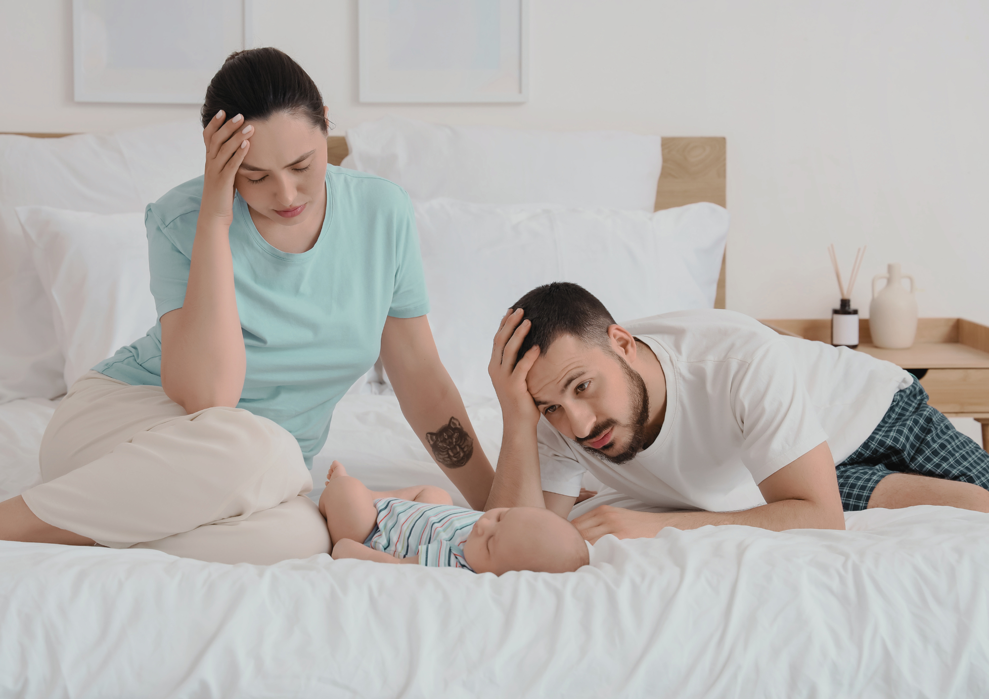 Tired new parents resting on the bed with their baby