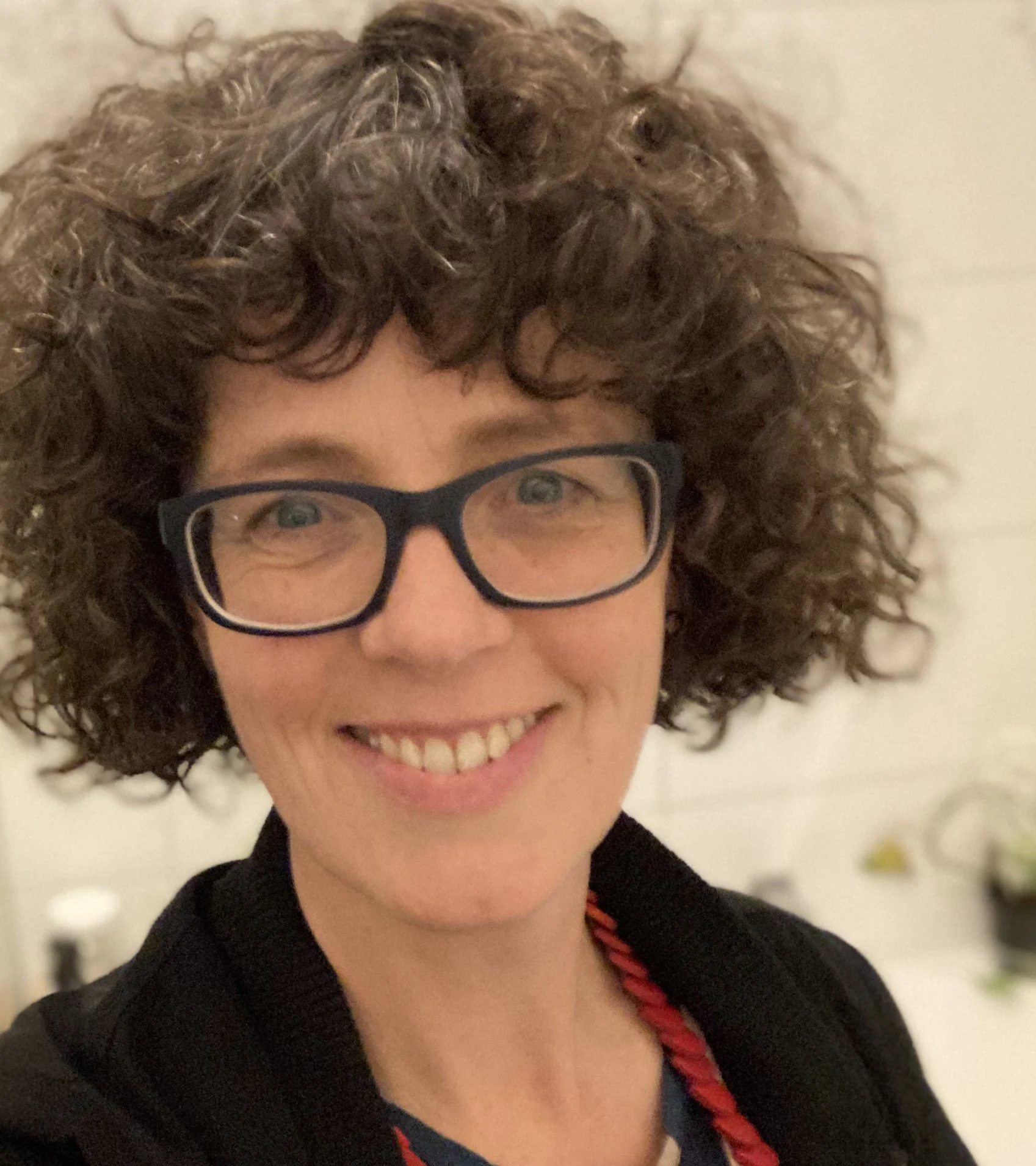 curly haired woman with glasses smiling at camera