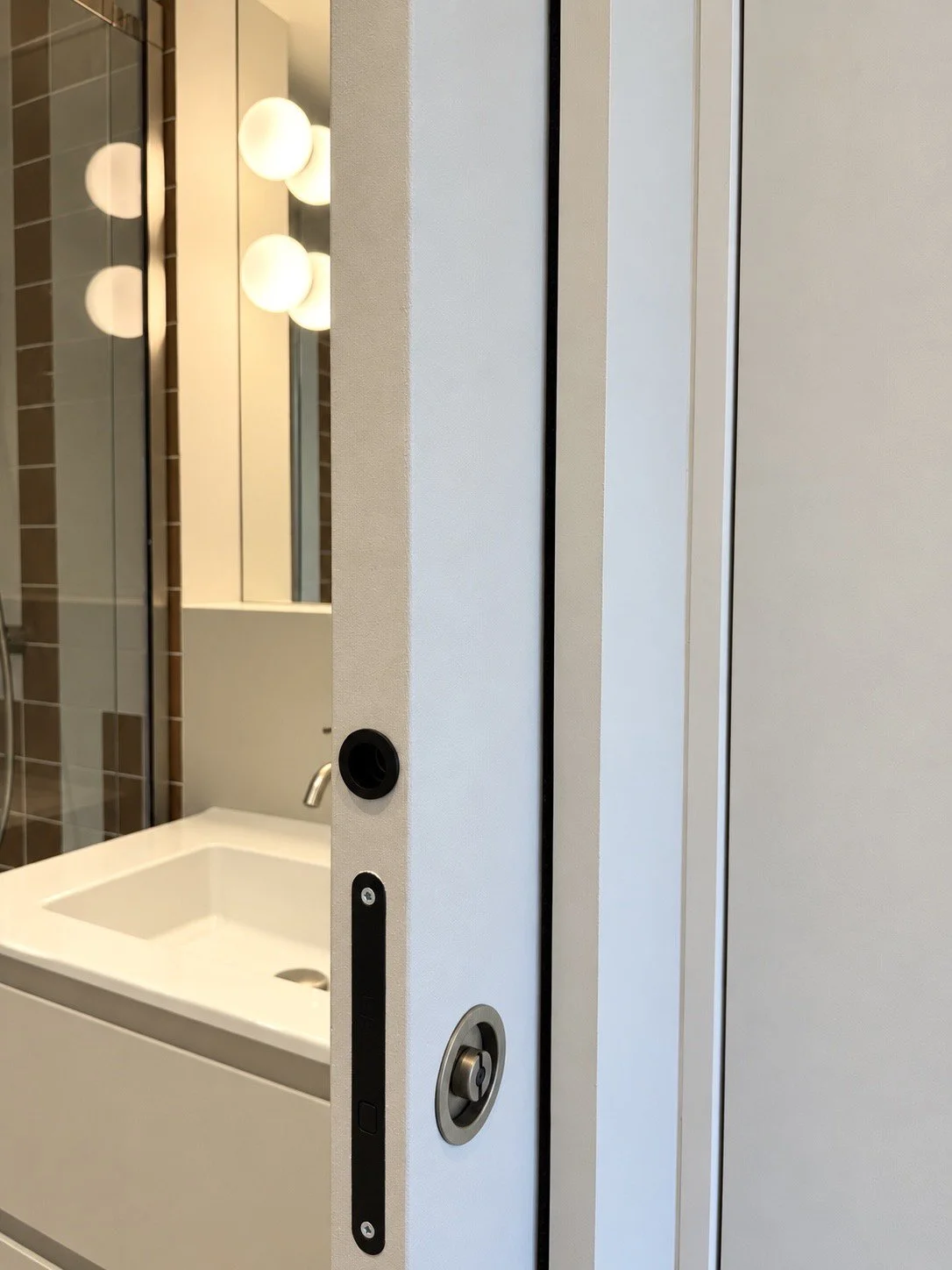 salle de bain avec miroir et applique globe en verre, porte coulissante à galandage.