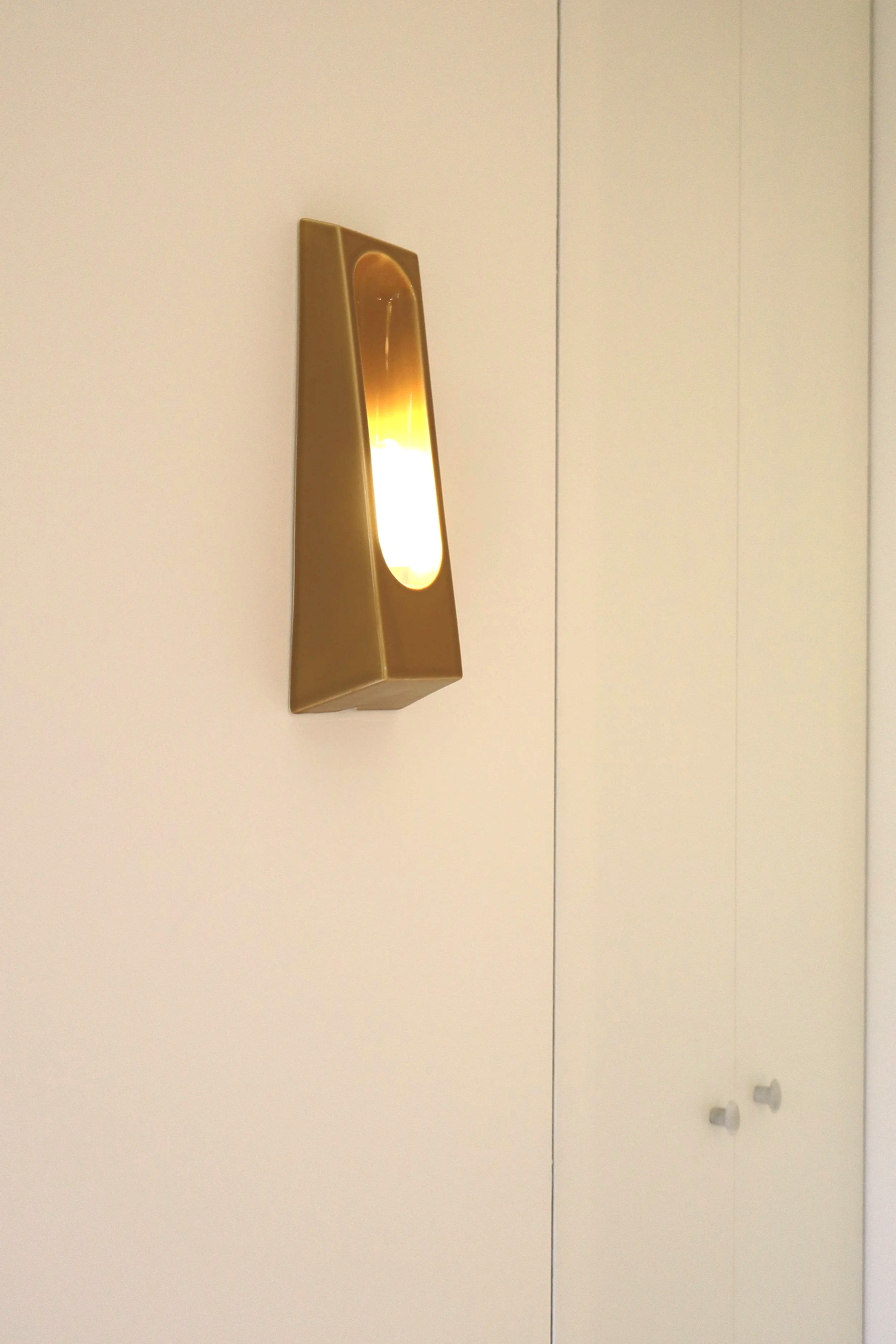 Lampe de mur en forme de pyramide dorée avec une lumière chaude