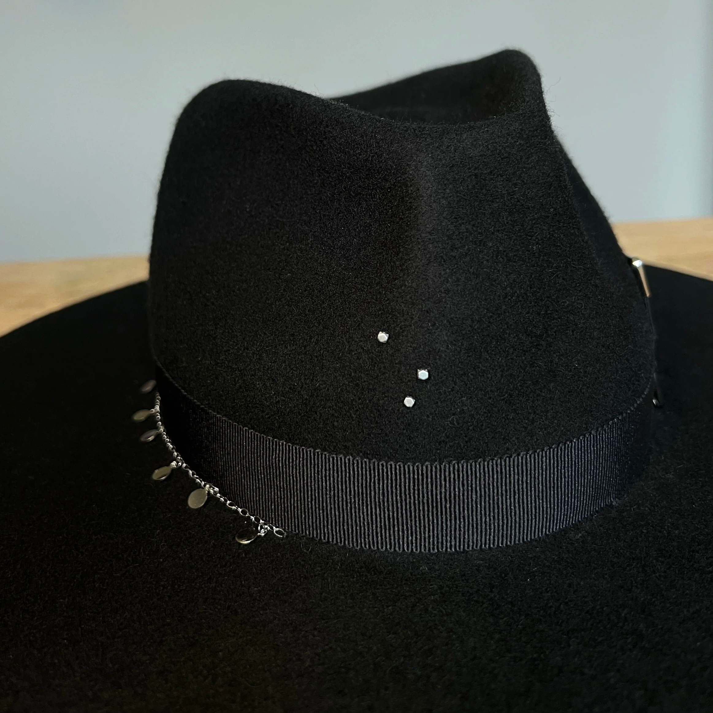 Minimalist black felt hat by Tihu, featuring wide brim and subtle silver embellishment.