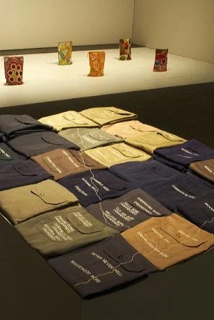 Front: Susanna Castleden, 'Abandoned (Near Wittenoom)' 2004. Embroidered work shirts on plinth. Rear: Irrunytju Artists, 'Untitled 1 - 12'. Calico geological sample bags, acrylic paint.
