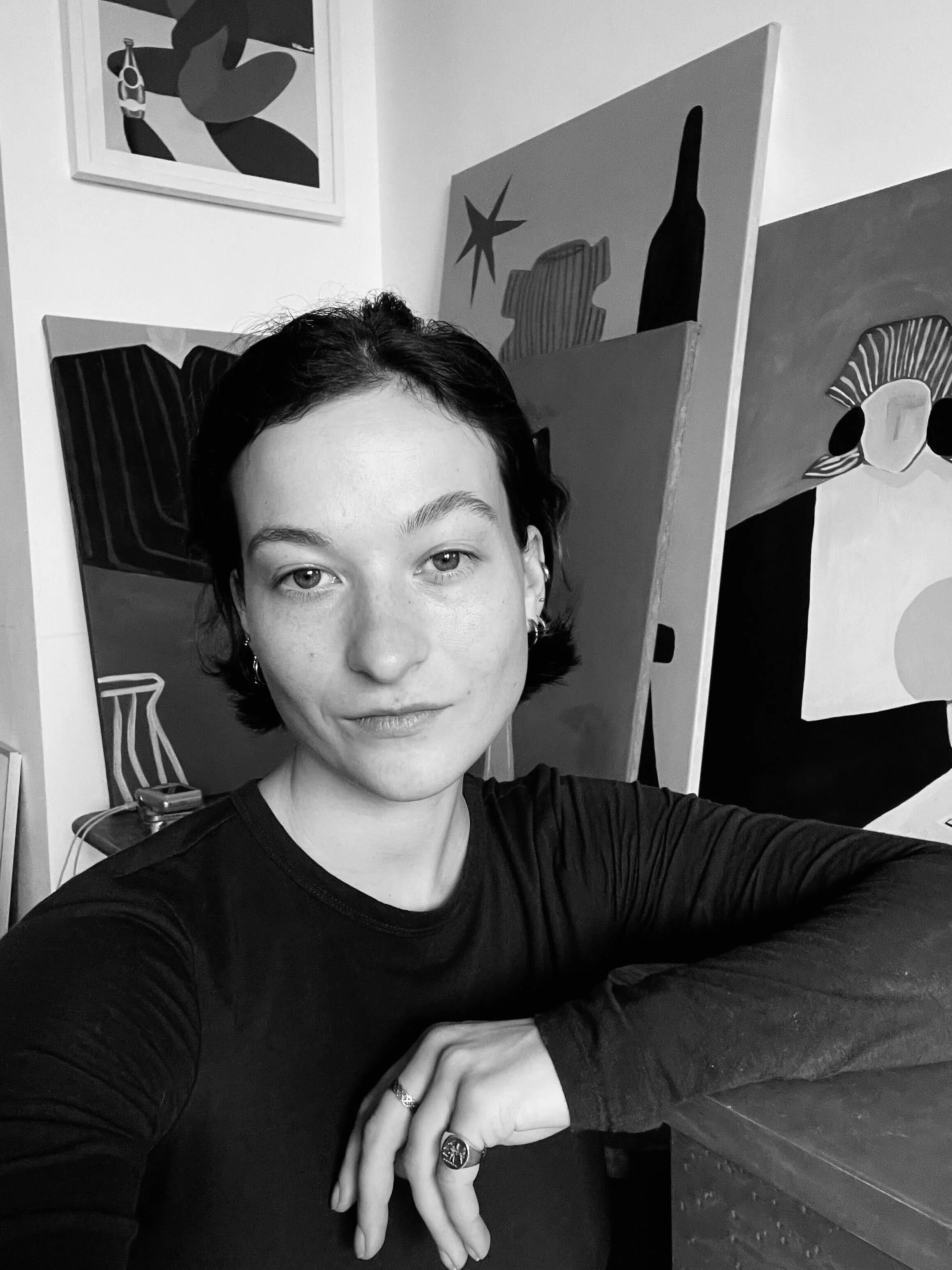 Molly Kayll, the Artist in front of colourful abstract paintings in an art studio.