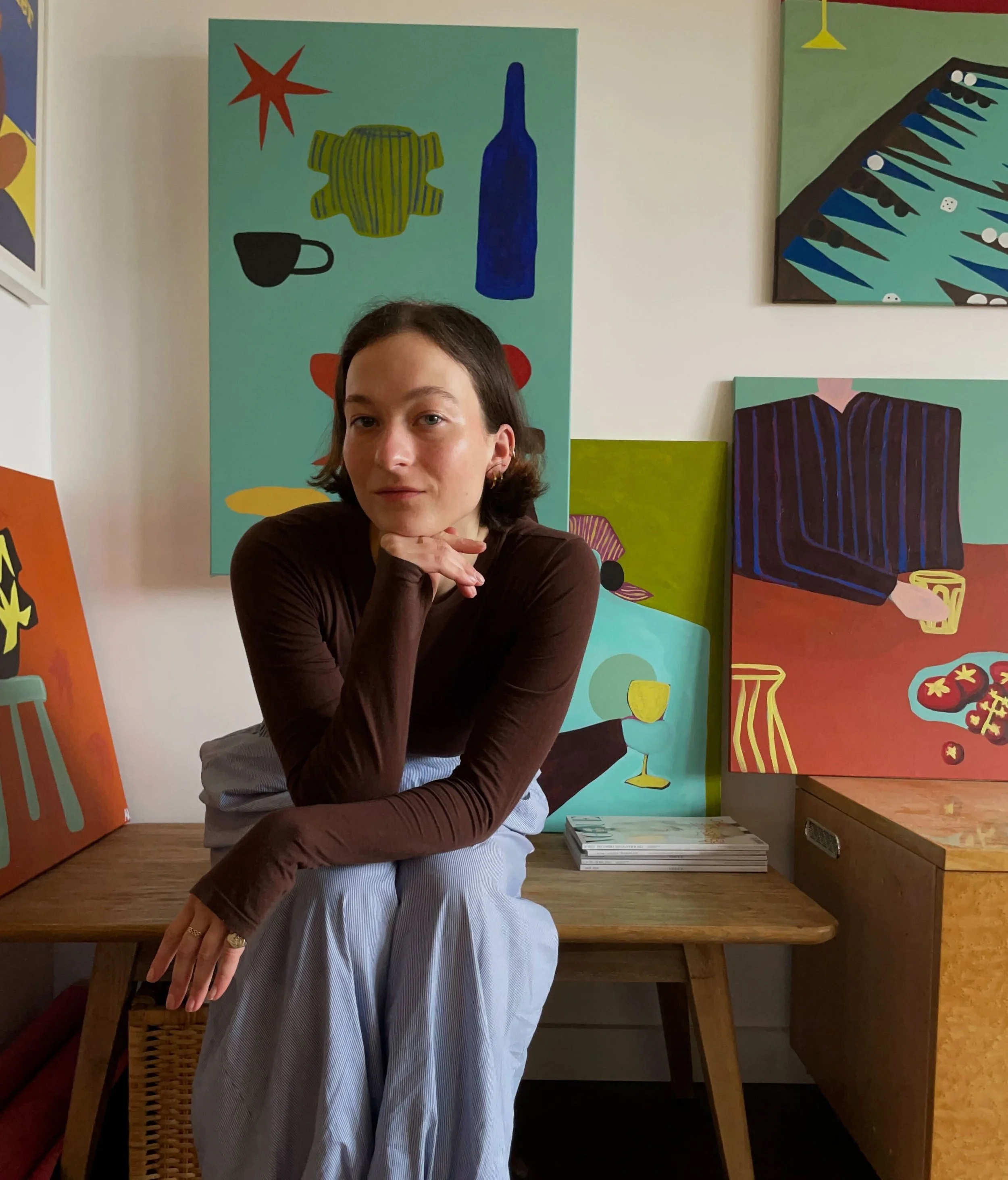 Molly Kayll, in an art gallery or studio, surrounded by colourful abstract paintings.