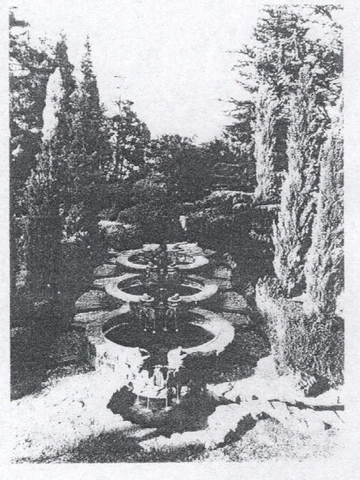 Fountain with multiple circular basins in a garden surrounded da alberi e vegetazione