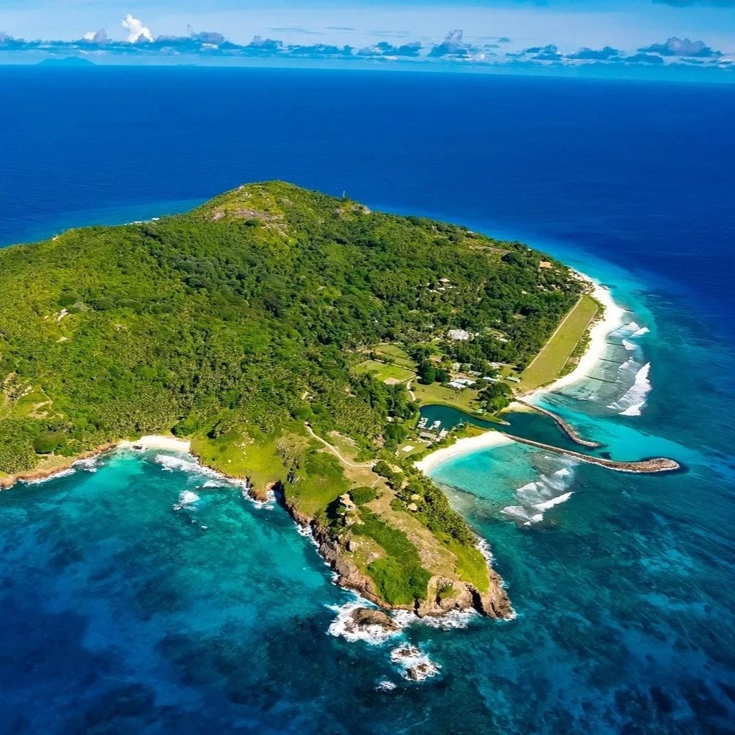 A tropical island with lush green vegetation, white sandy beaches, and surrounding turquoise blue waters.