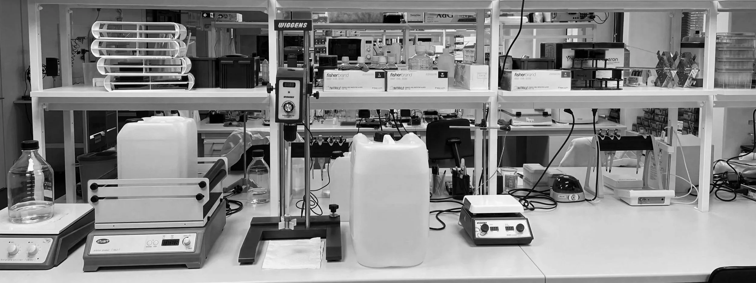 Laboratory workspace with scientific equipment including glass beakers, a hot plate, and various electronic devices.