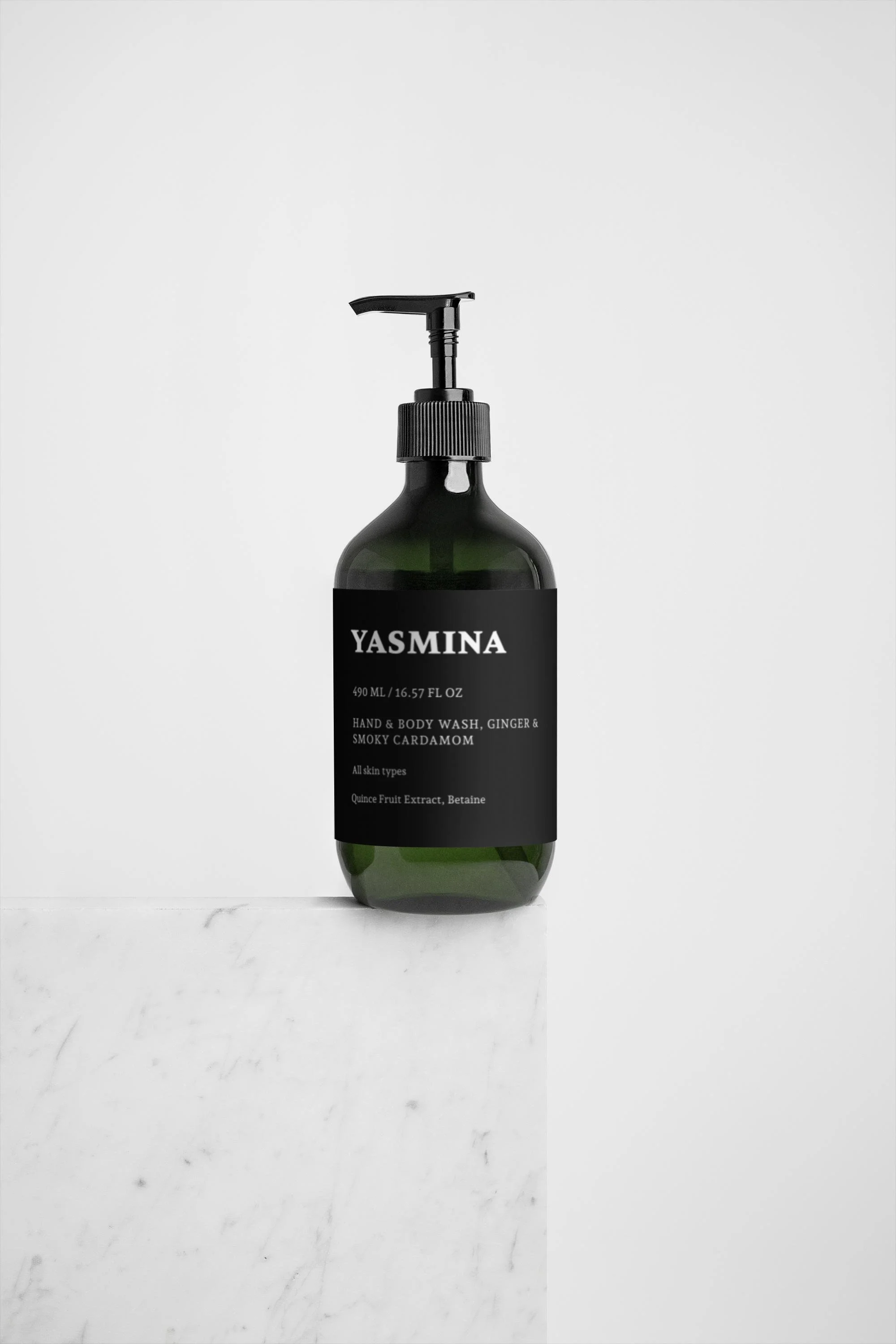 En grøn flaske med pumpe, mærket 'YASMANA', indeholder hånd- og kropsvask med ingefær og røgfyldt kardemomme.
