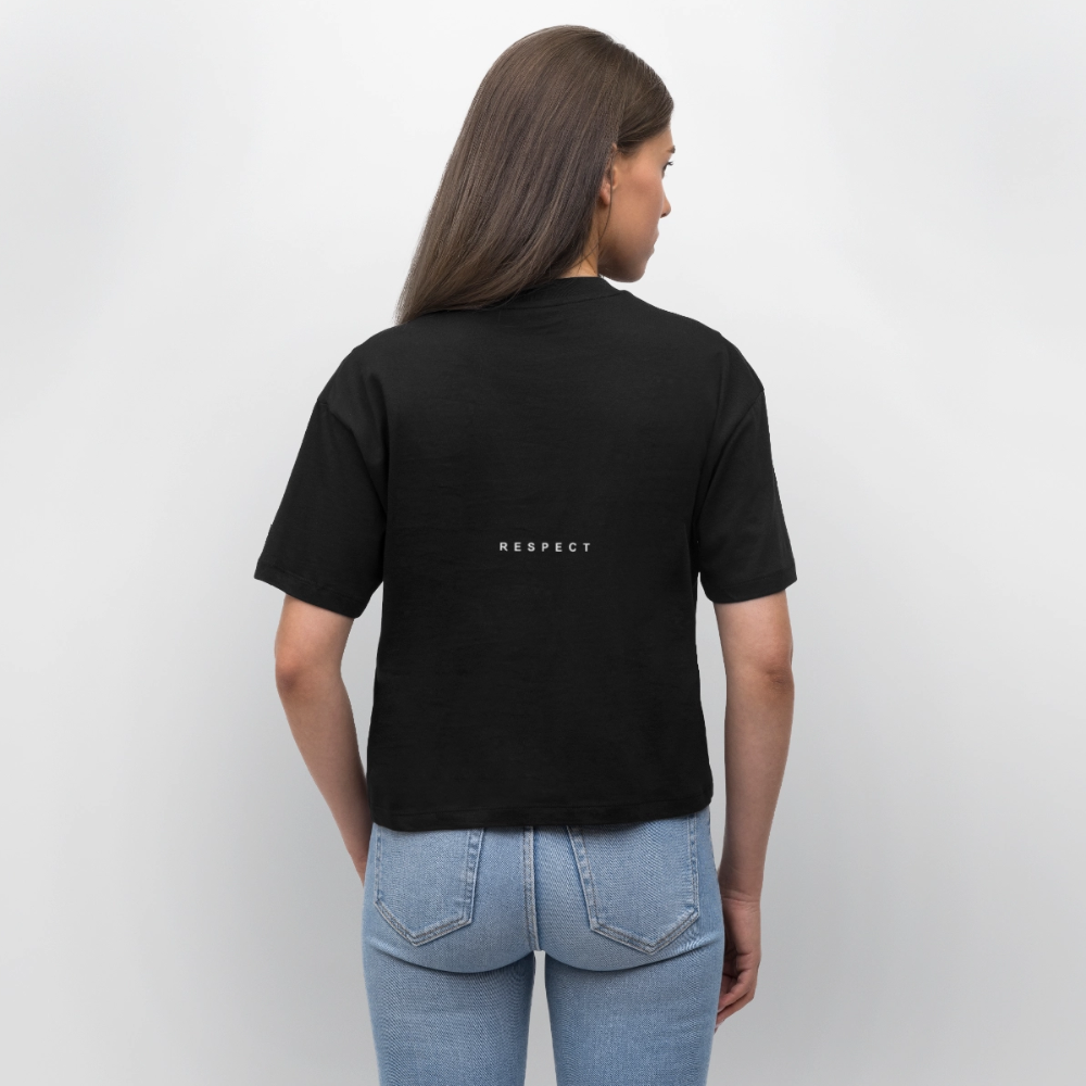 Et billede af en kvinde set bagfra, iført en sort T-shirt med teksten 'RESPECT' på ryggen og lyse blå jeans.