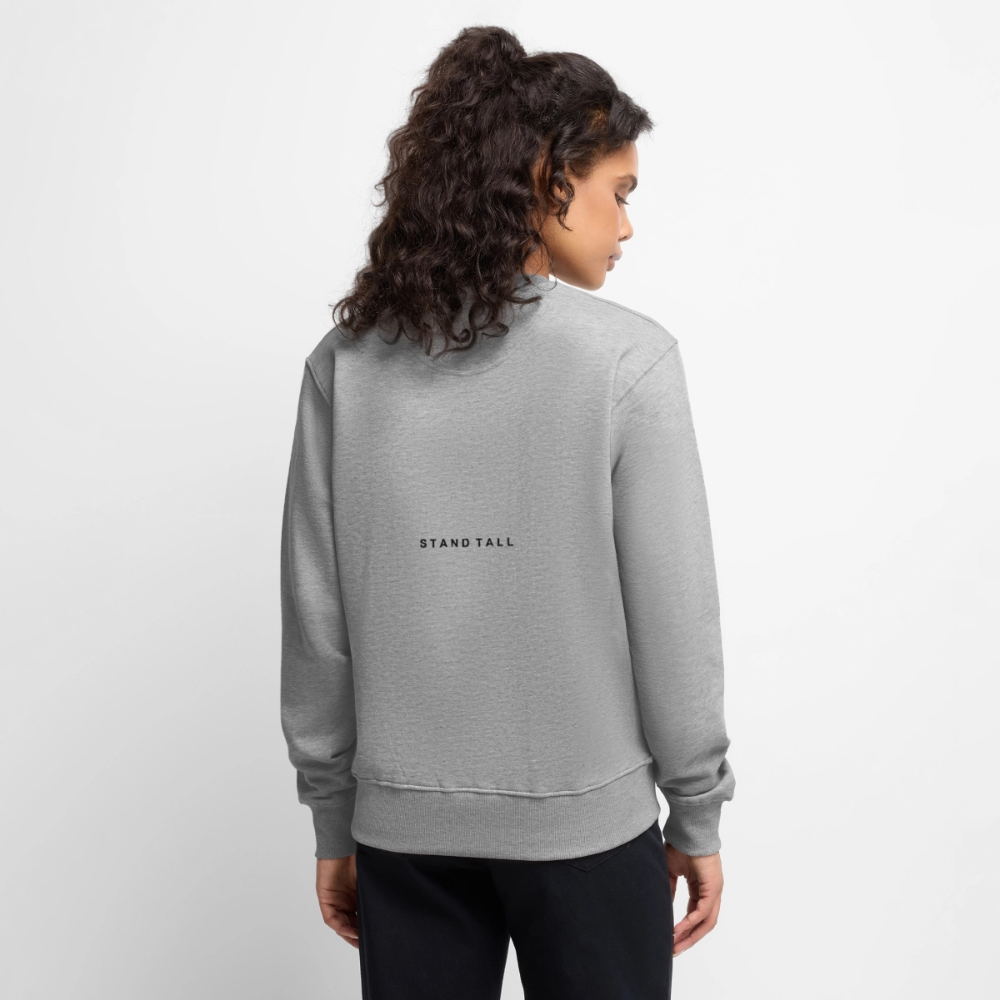 En person med langt, krøllet hår iført en grå sweatshirt med teksten 'STAND TALL' set bagfra.