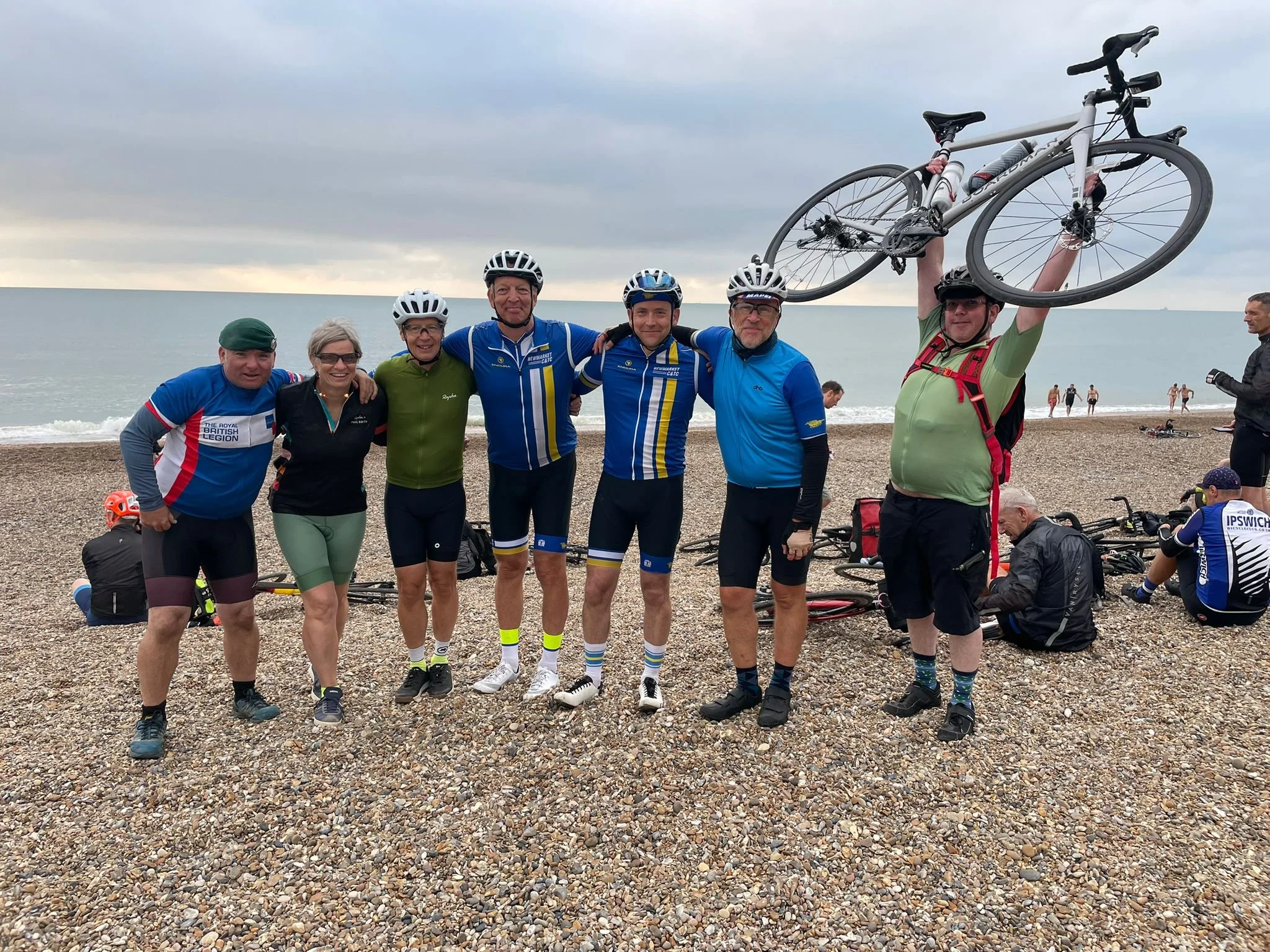 Smiling NC&TC members with their bikes on a shingle beach at the end of a club ride to the coast