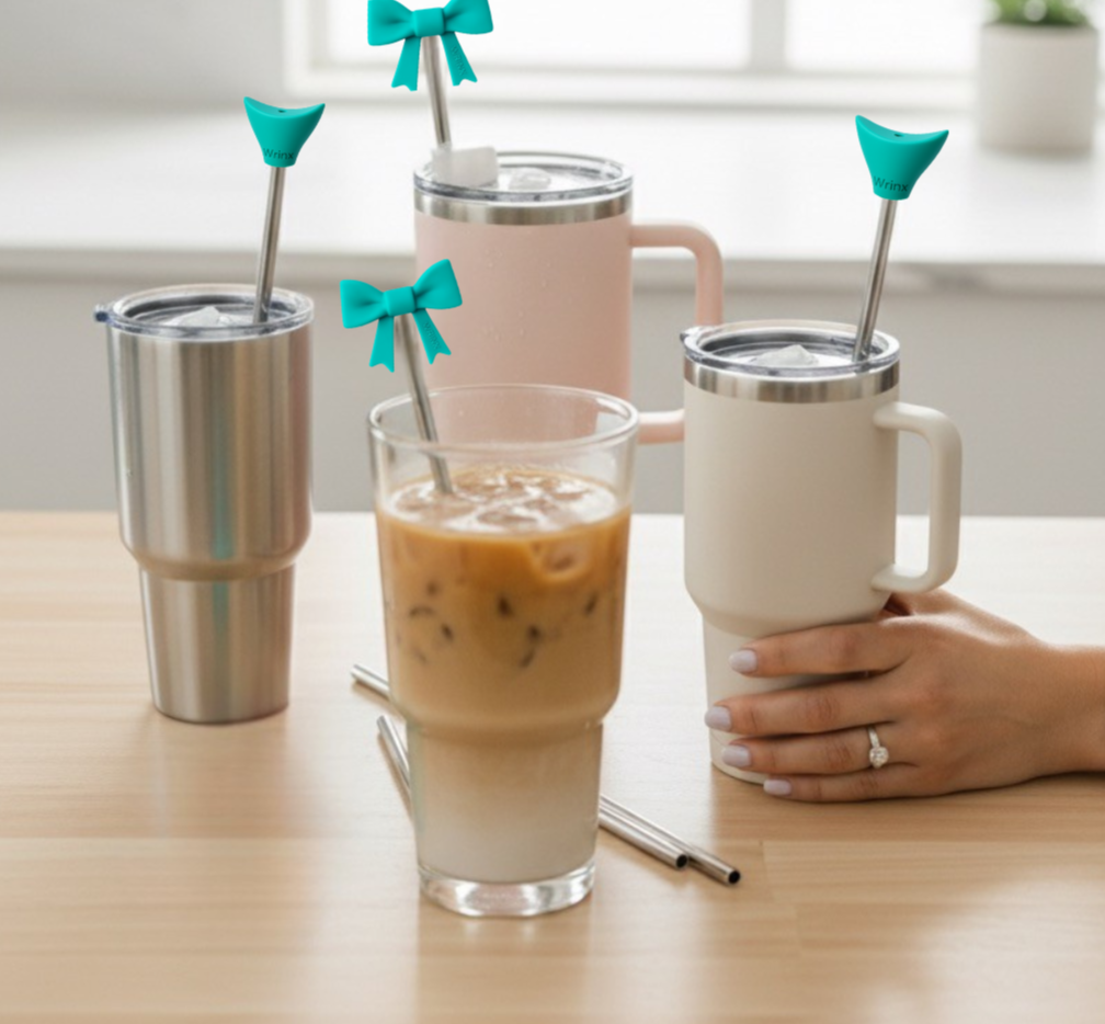 3 tumblers and one cup on a kitchen table. all with stainless steel straws and wrinx straw attachments on them