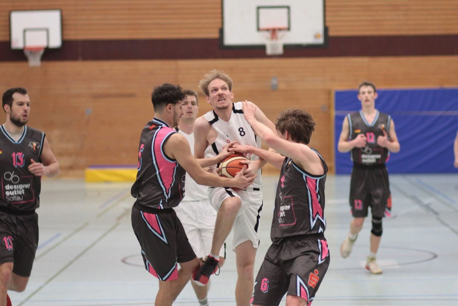 Basketballspieler im Kampf um den Ball während eines Spiels in einer Turnhalle.