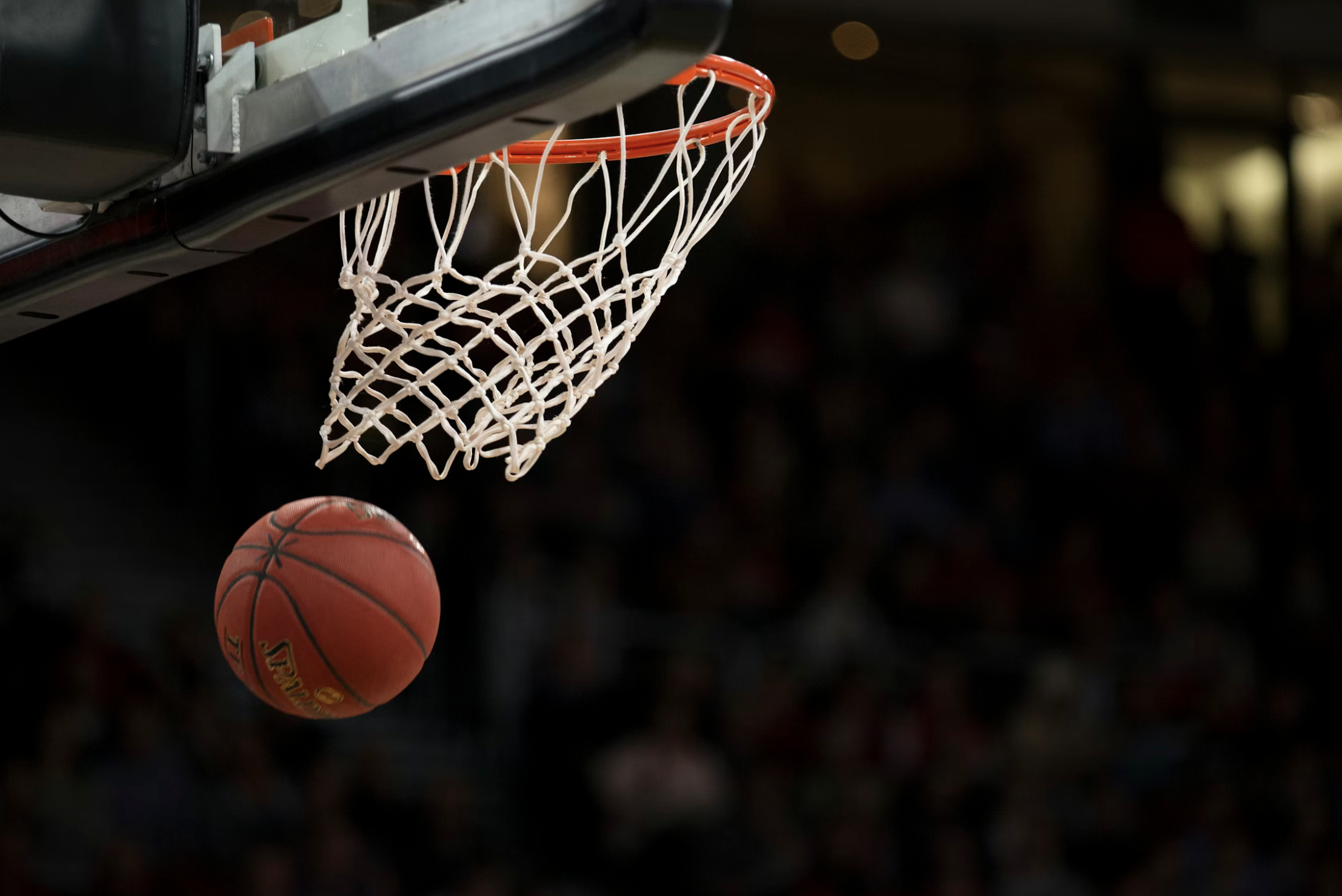 Ein Basketball hängt an einem Brett, während eine weitere Basketball im Flug auf den Korb zufliegt.