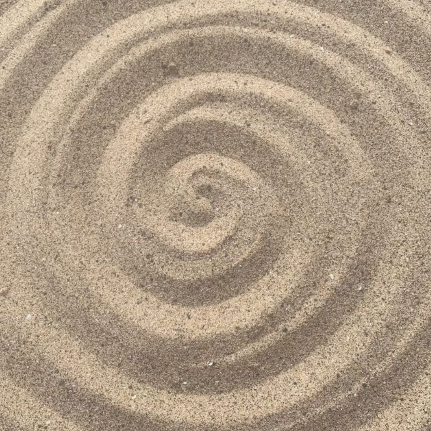 Close-up view of sand arranged in concentric circles, resembling a ripple effect in the sand.