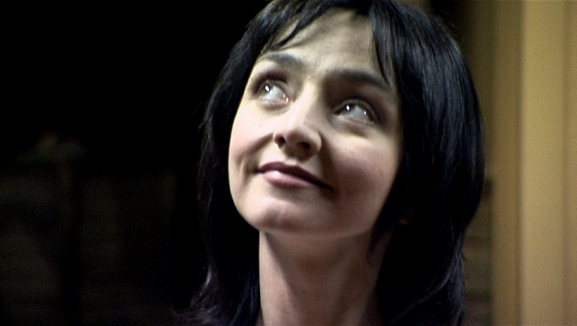Close-up of actress Maria De Medeiros looking upward with a slight smile.