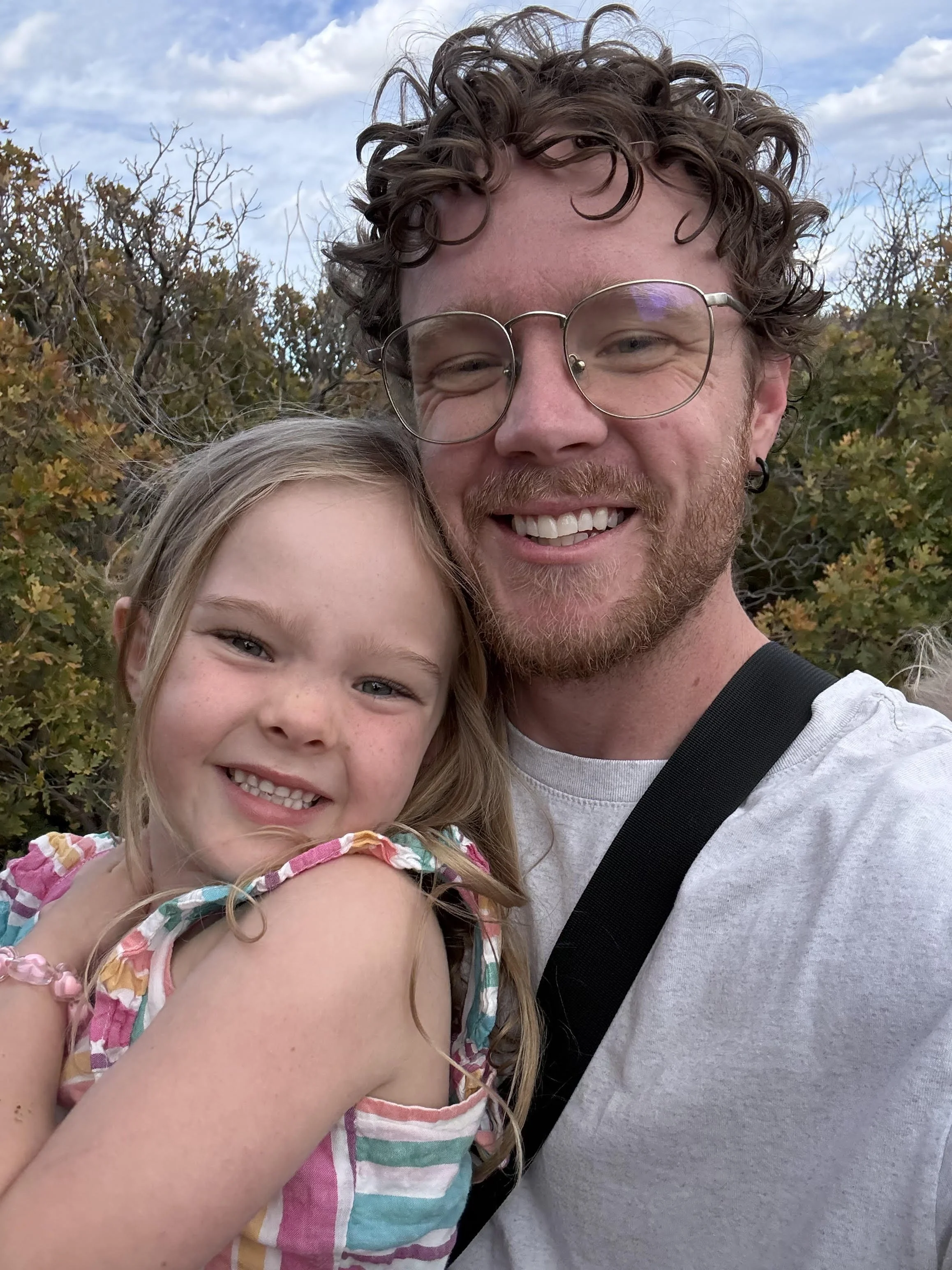 Sew Far, So Good, with his inspirational daughter.  He is a home crafter that loves making teddy bear dresses and overalls for her daughter.  They are smiling while looking at the camera.